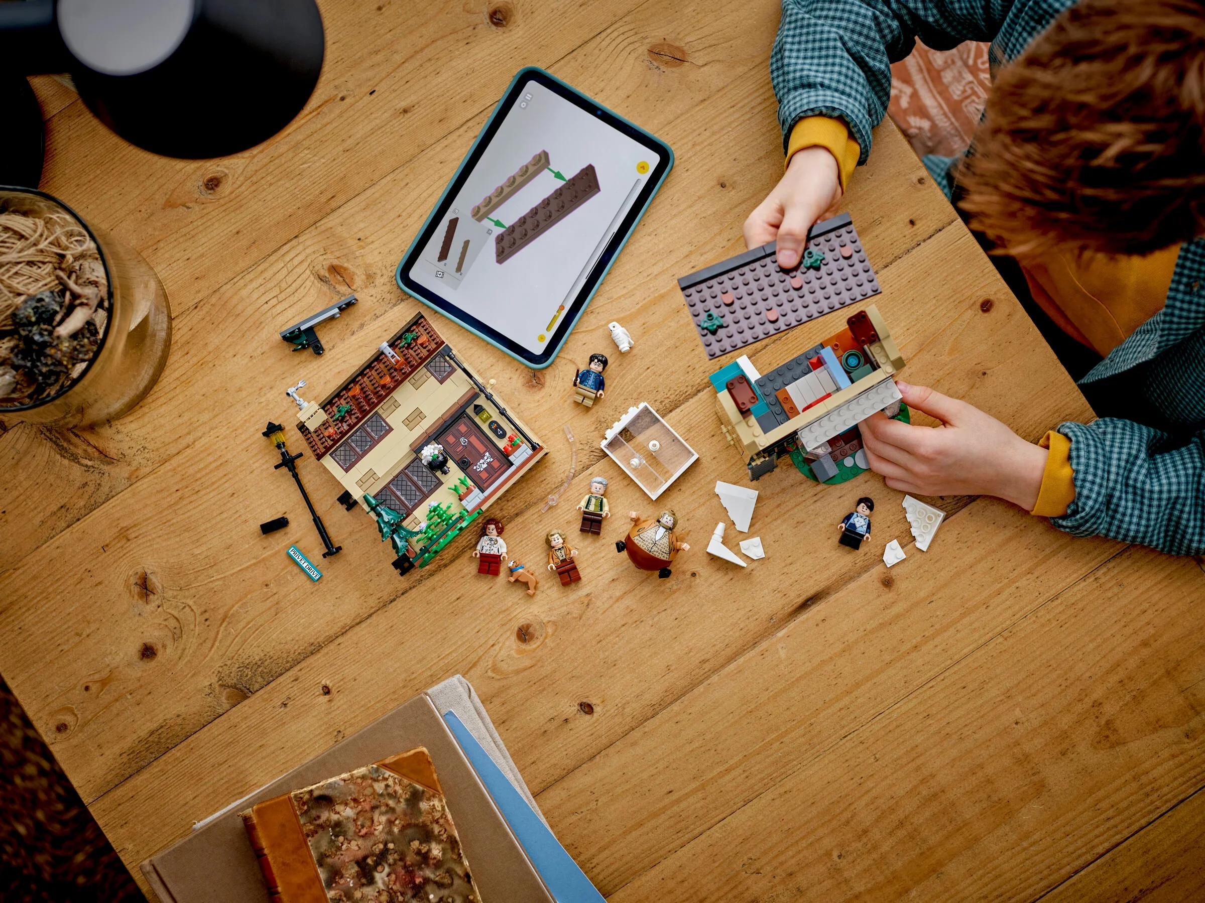 Copil construind casa de la Privet Drive cu instrucțiuni digitale pe tabletă.