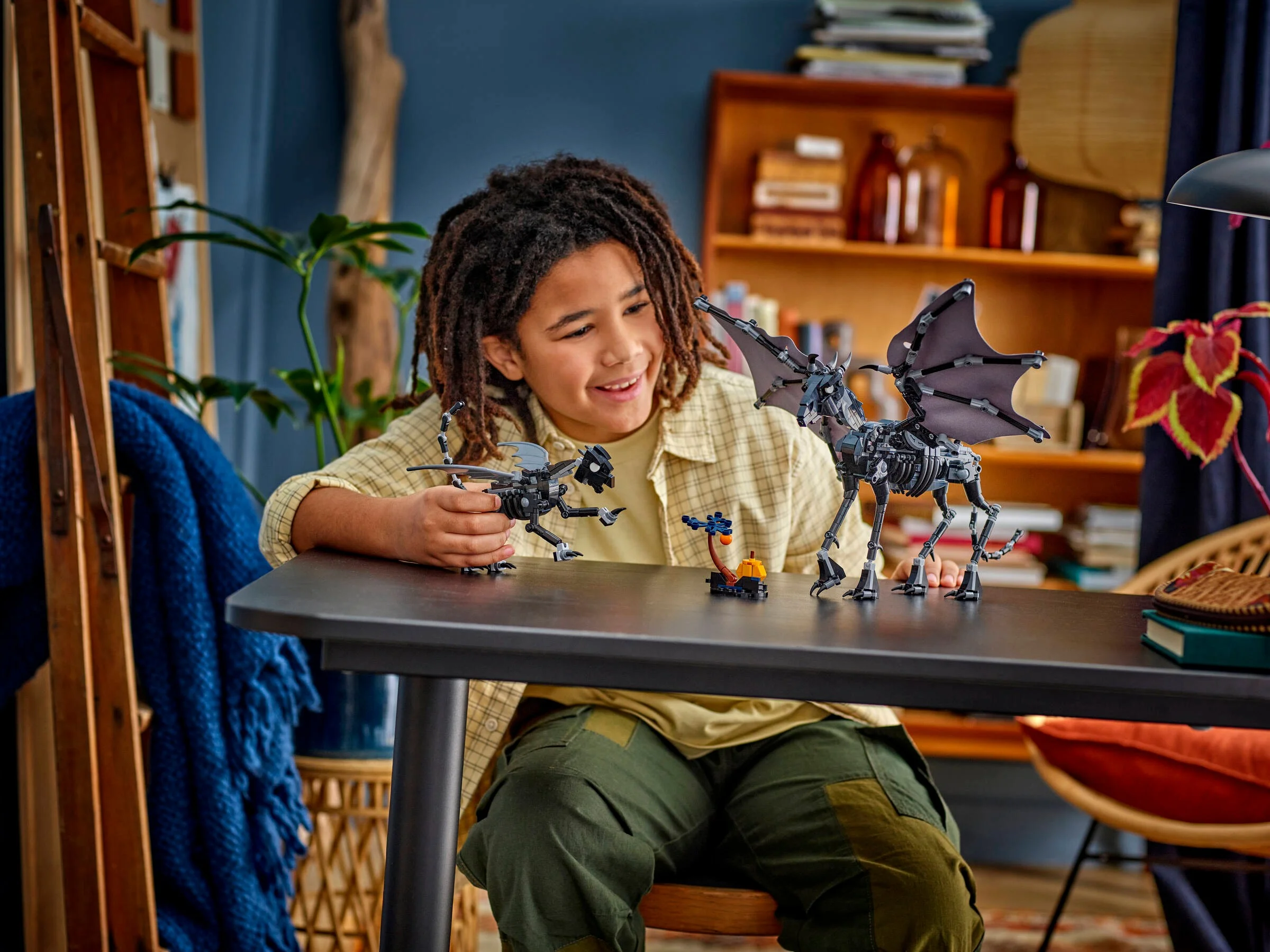 Copil zâmbind în timp ce se joacă cu setul LEGO Thestral Family. Bucurie și creativitate!