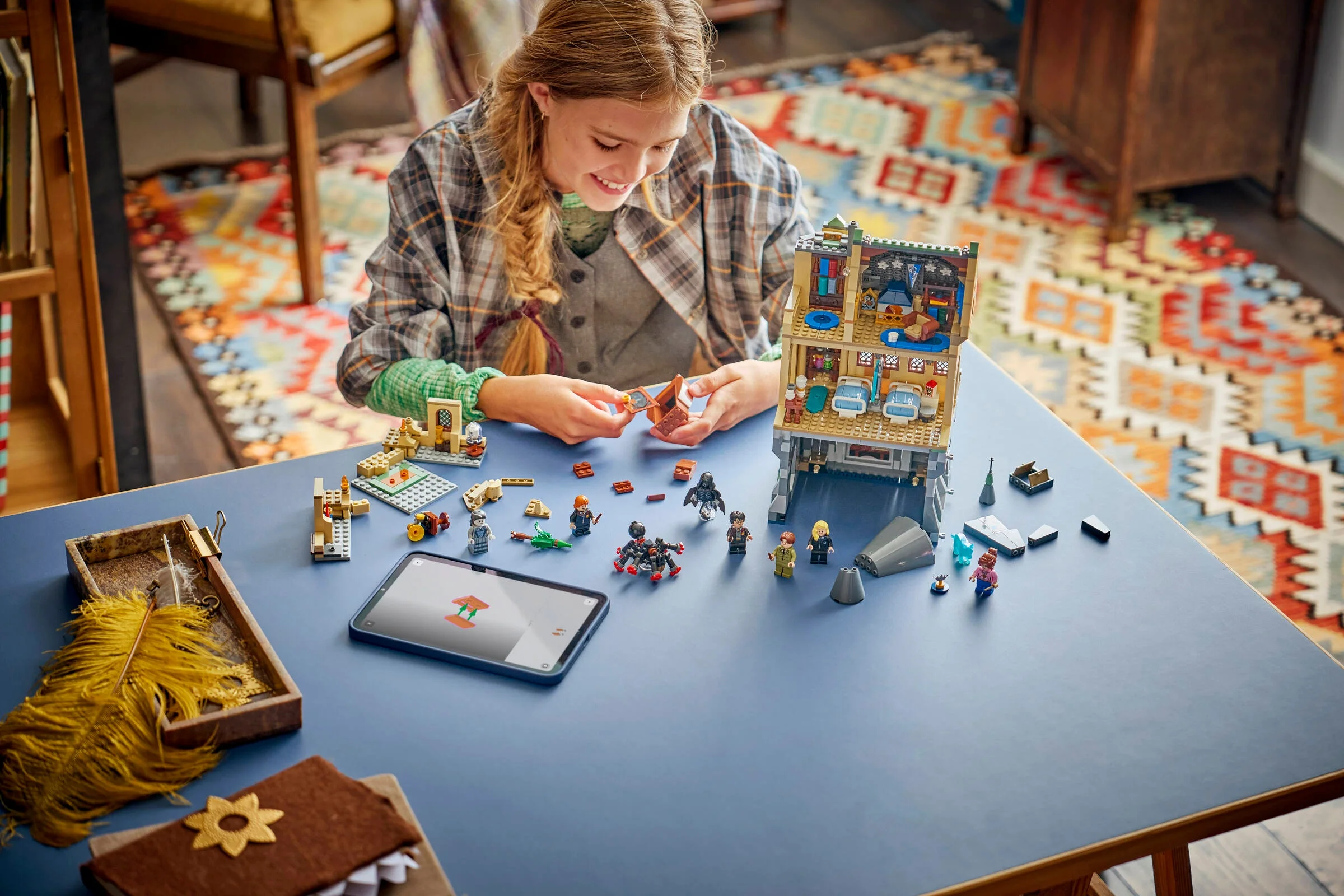Fată construind aripa spitalului Hogwarts LEGO. Setul include minifigurine și detalii interactive.