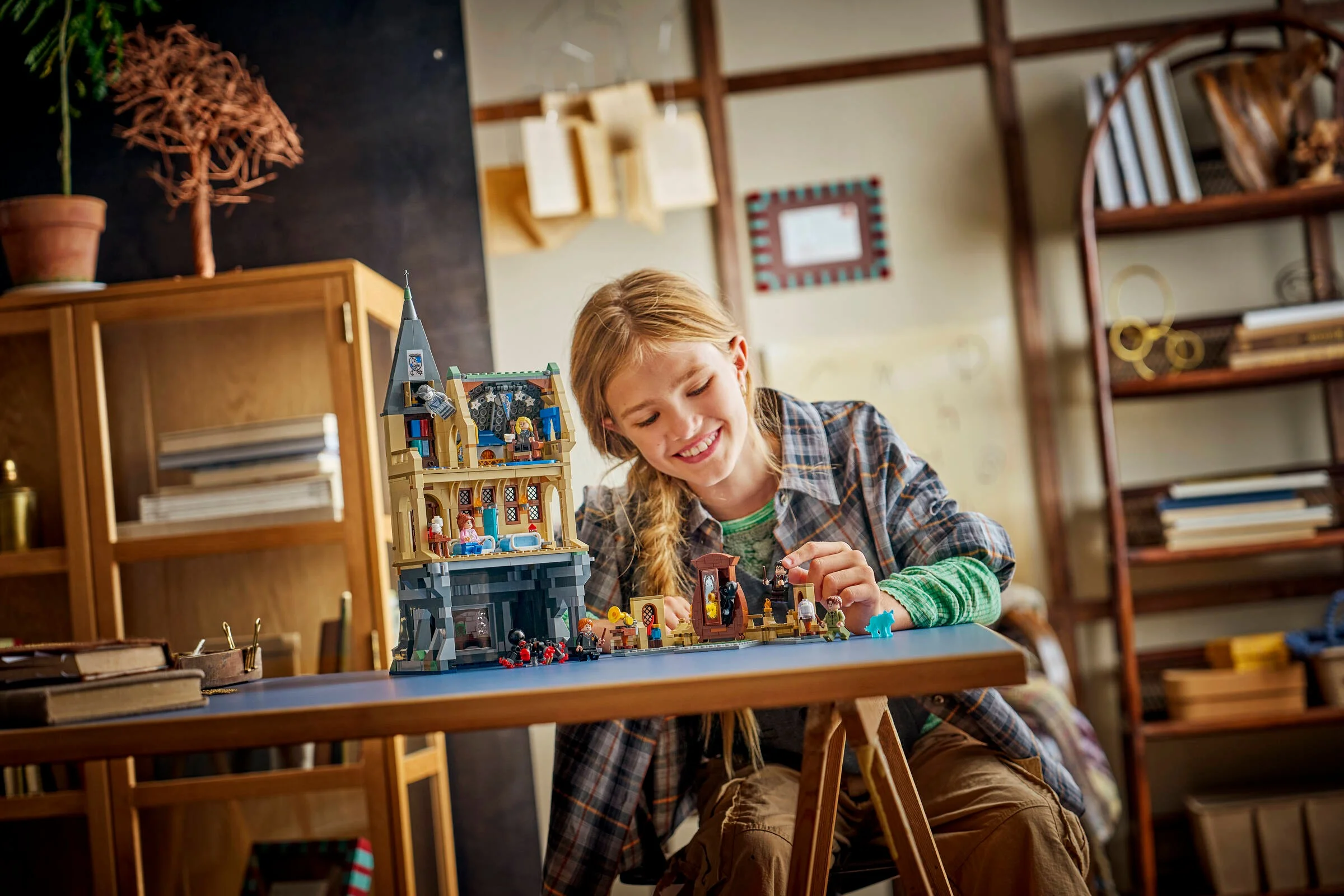 Fată construind Castelul Hogwarts - Aripa Spitalului. Zâmbește, e concentrată la joacă.