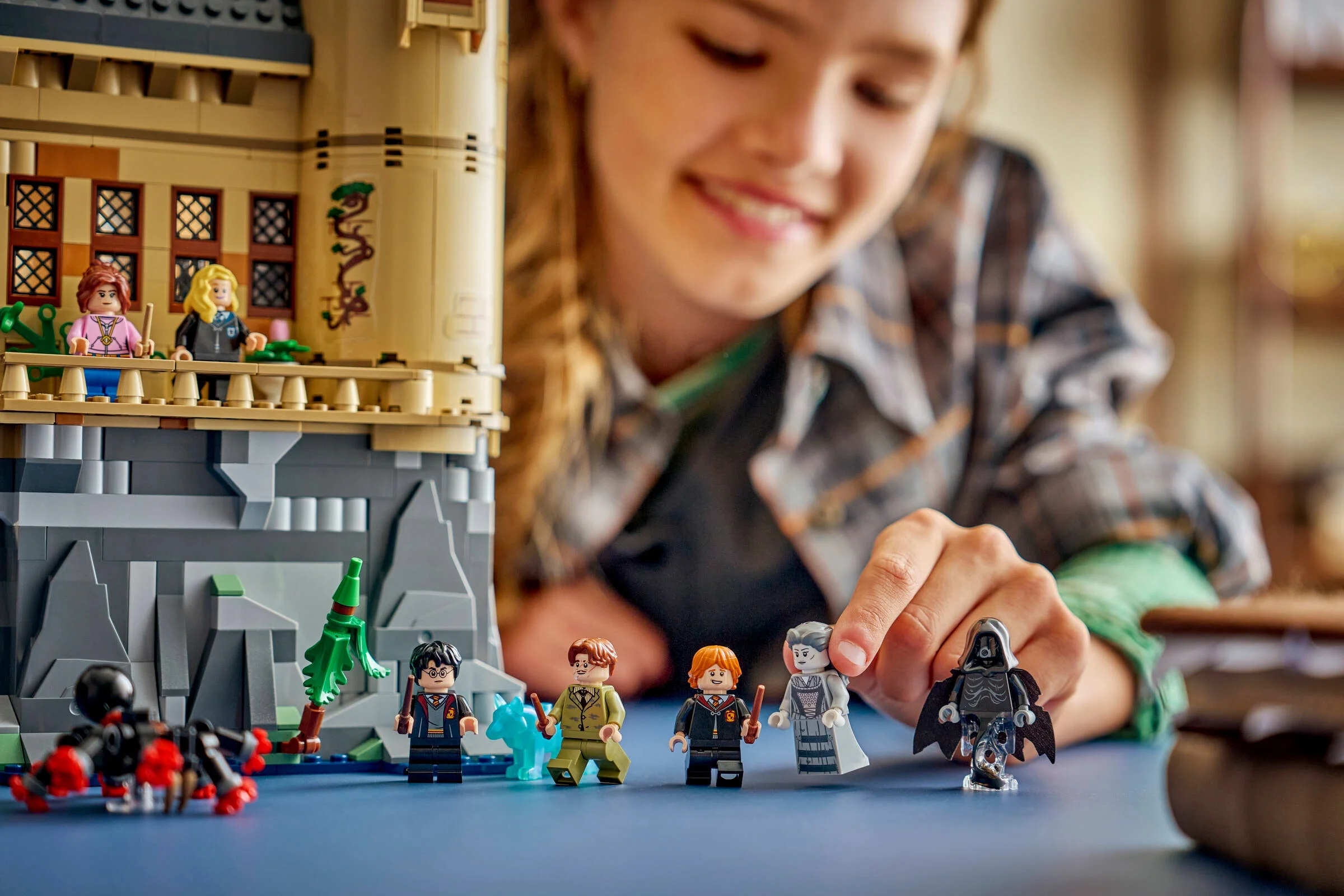 Setul LEGO Hogwarts Castle: Hospital Wing cu minifigurine și un copil zâmbitor în fundal.