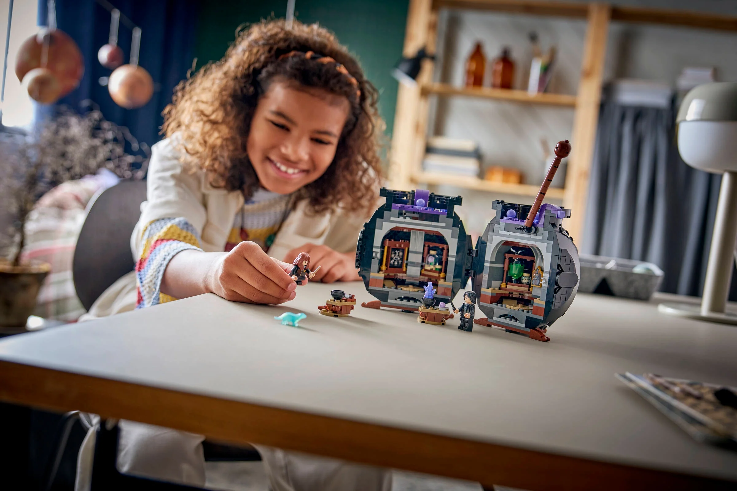 O fetiță zâmbitoare se joacă cu setul LEGO Laboratorul de Poțiuni.