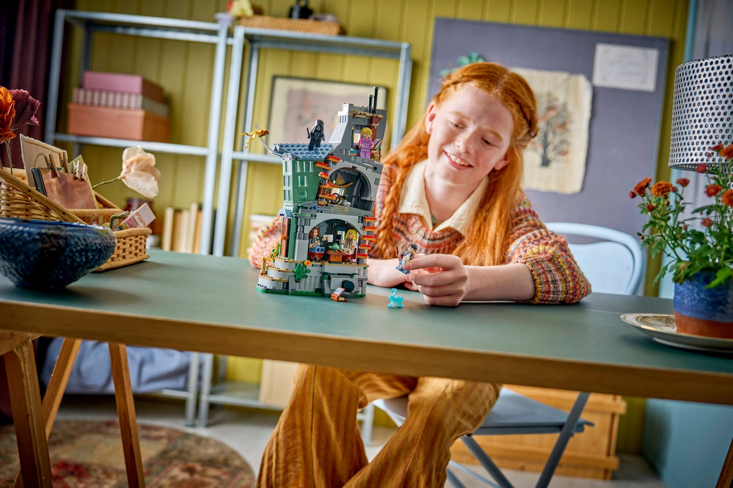 O fată se joacă cu setul LEGO Luna Lovegood, zâmbind și ținând o minifigurină.