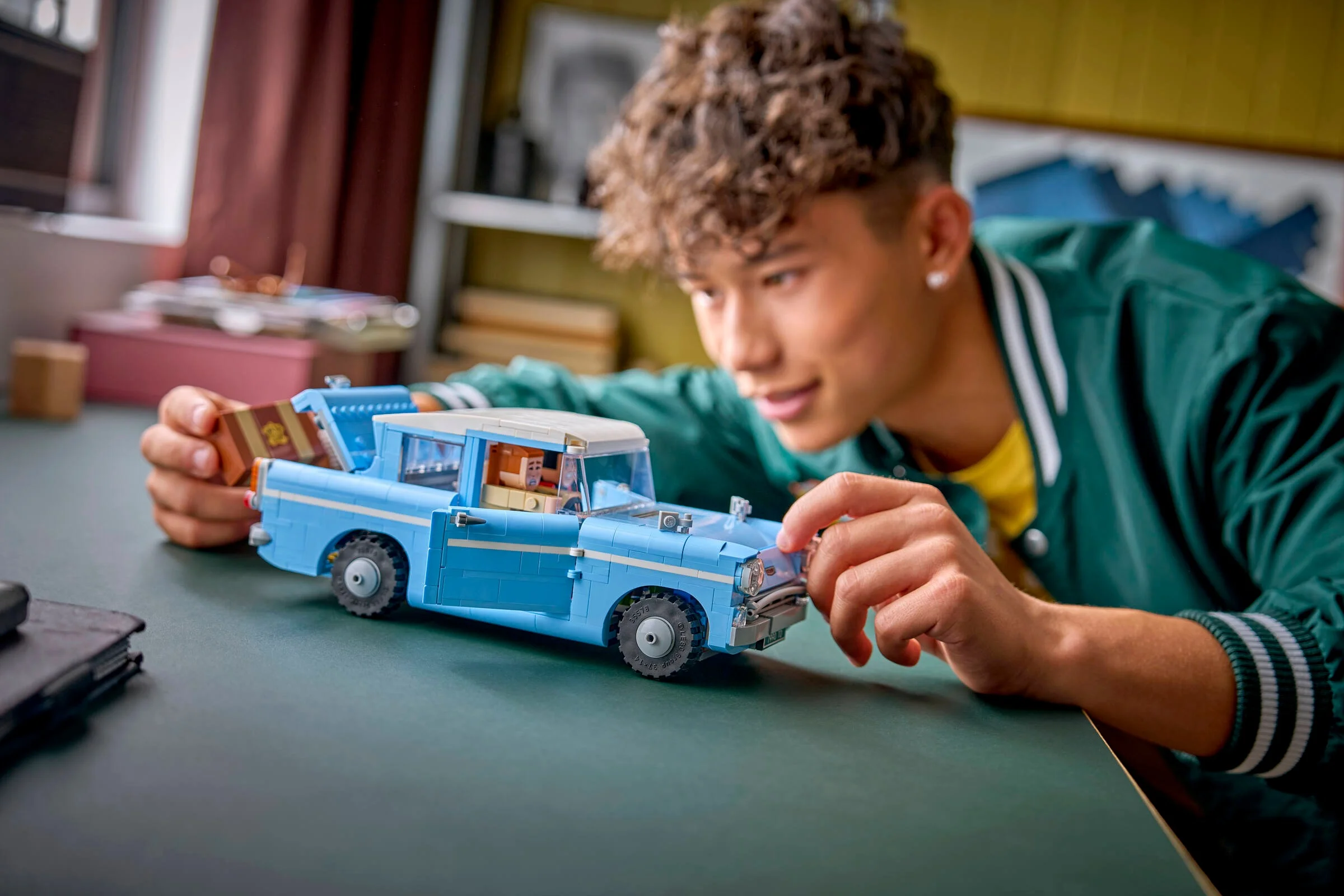 Un tânăr interacționează cu Ford Anglia zburătoare, modelul LEGO 76470, într-o scenă lifestyle.