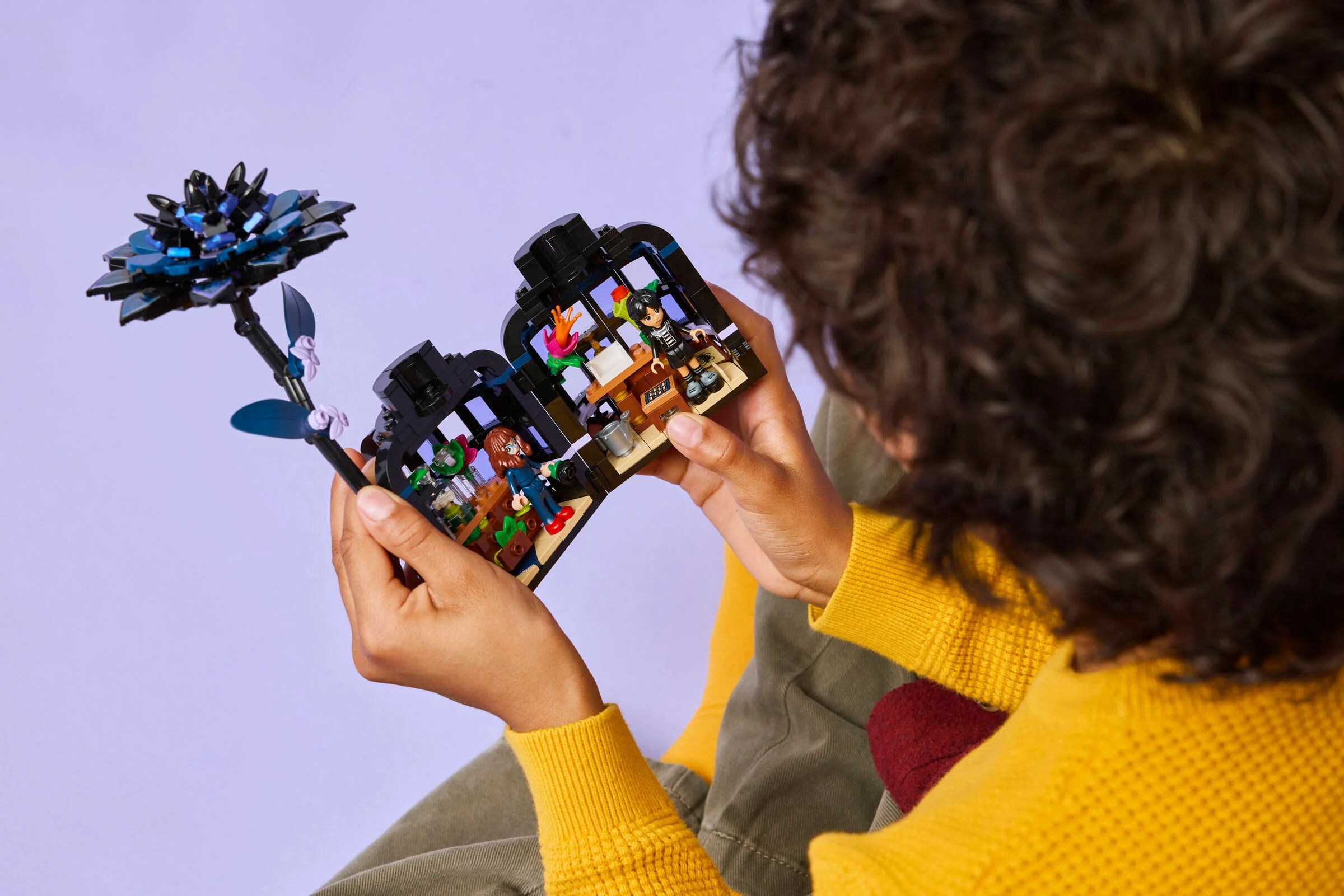 Imagine cu persoană ținând setul LEGO Black Dahlia Flower, arătând minifigurinele și detaliile florale.