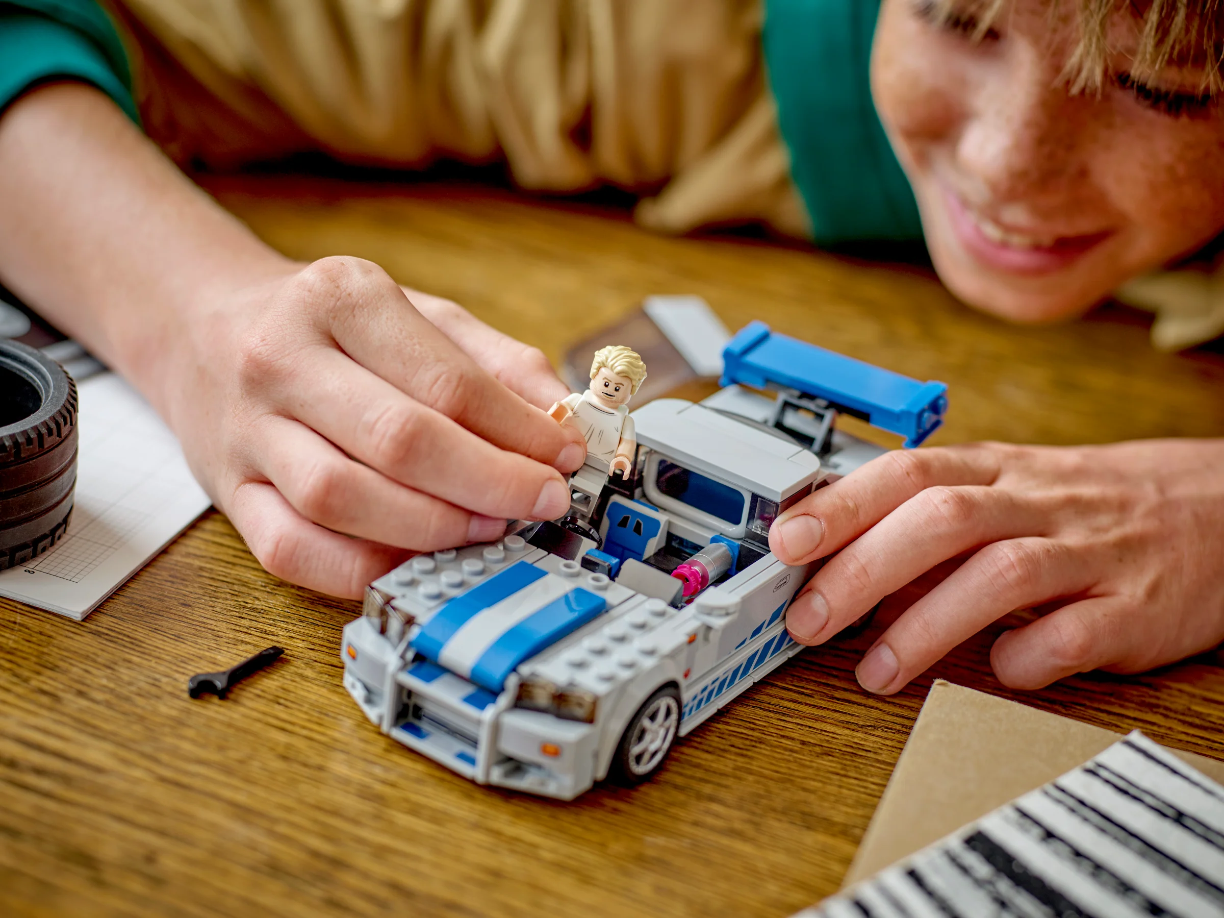 Un copil așează minifigurina Brian O'Conner în mașina Nissan Skyline GT-R (R34).