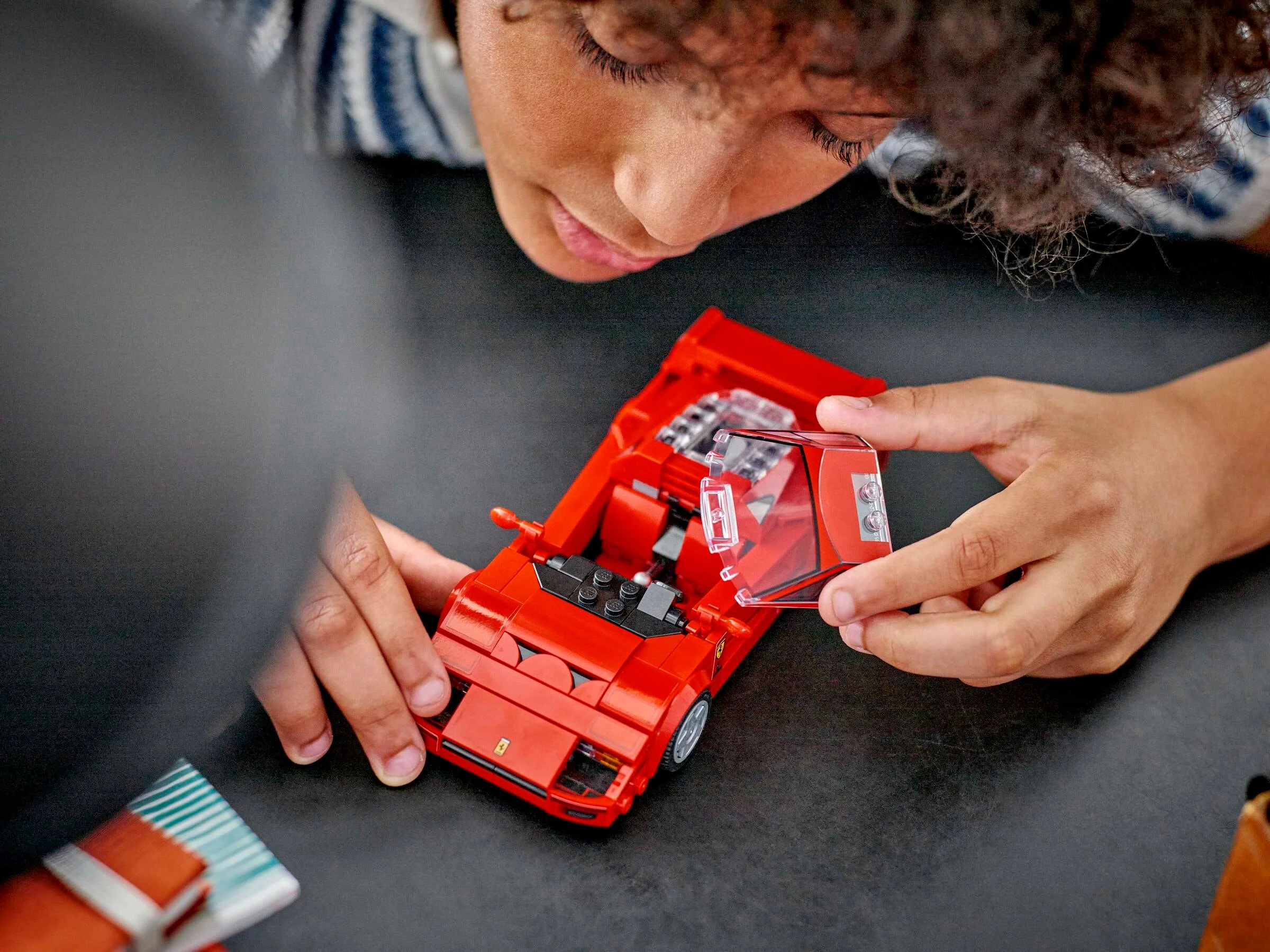 Copil asamblând modelul Ferrari F40 Speed Champions. Detaliu cu geamul montat.
