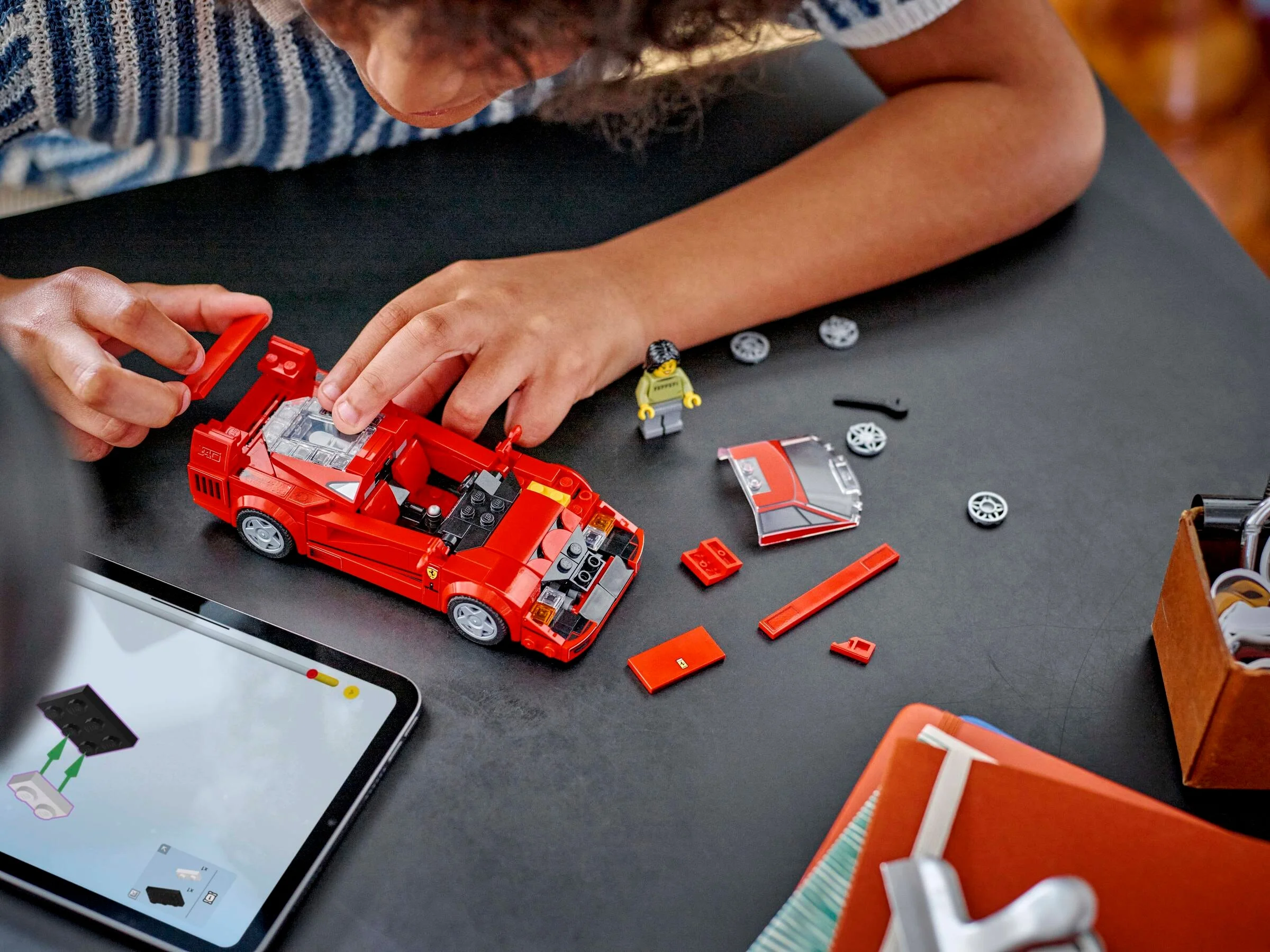Copil construind Ferrari F40 cu instrucțiuni digitale pe tabletă. Detaliu interesant.