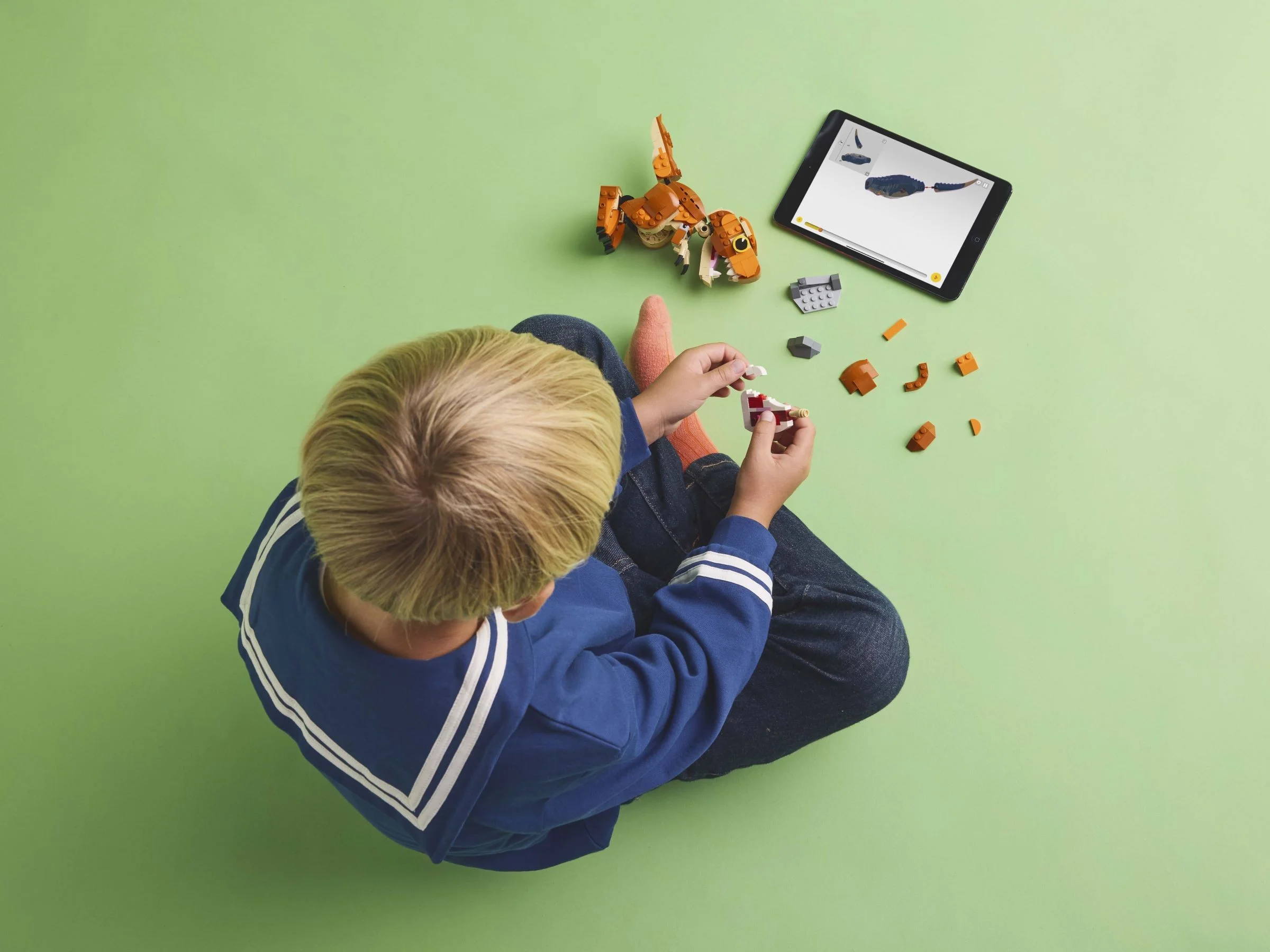 Copil construind Little Eatie: T. rex. Instrucțiuni digitale pe tabletă.