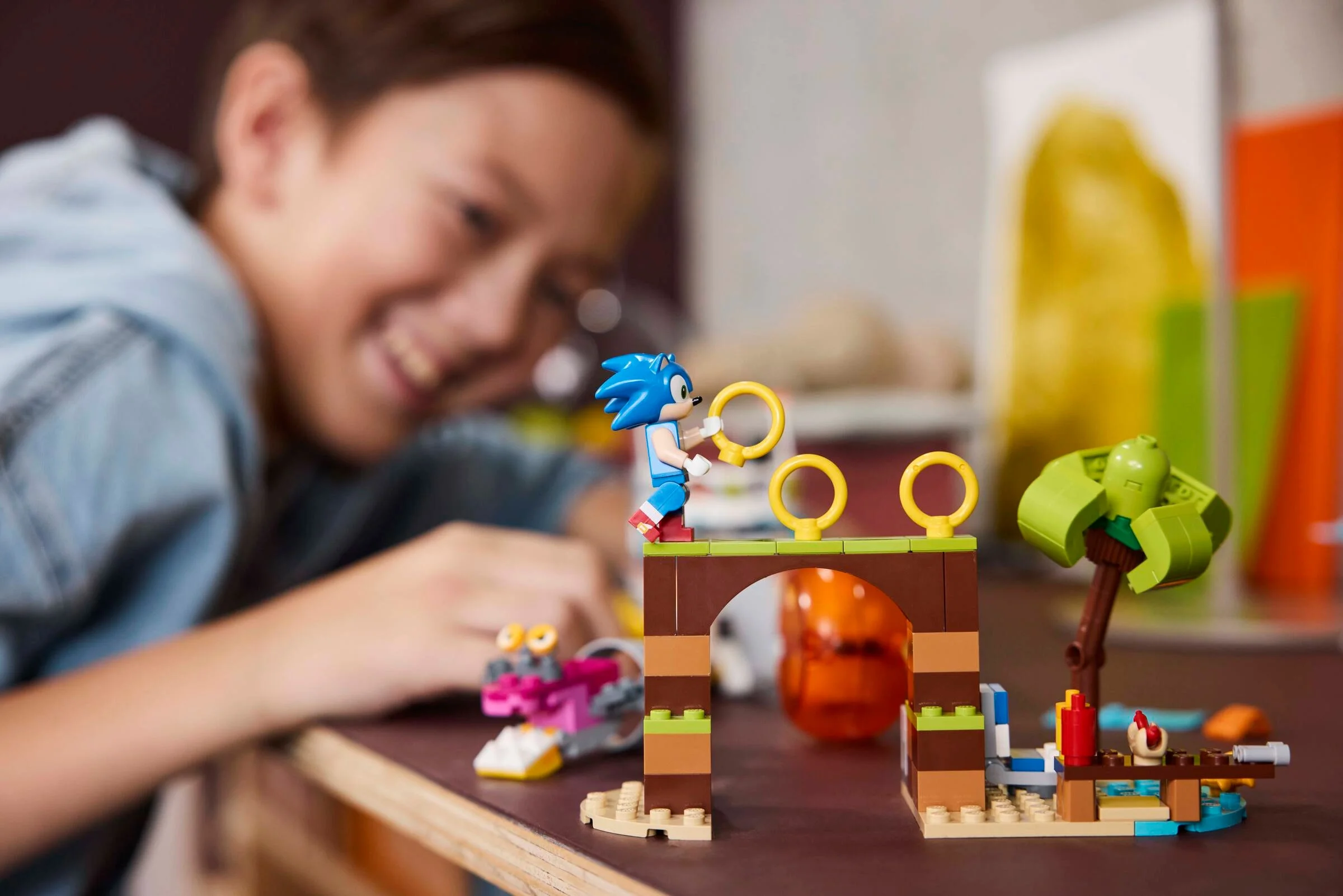 Imagine cu un copil construind setul LEGO Sonic cu Sonic alergând spre inele.