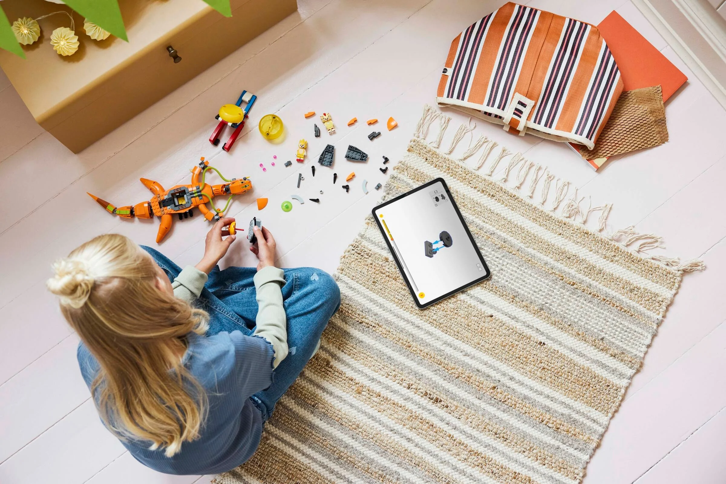 Fetiță asamblând setul LEGO Super Shadow vs. Biolizard folosind instrucțiuni digitale pe tabletă.