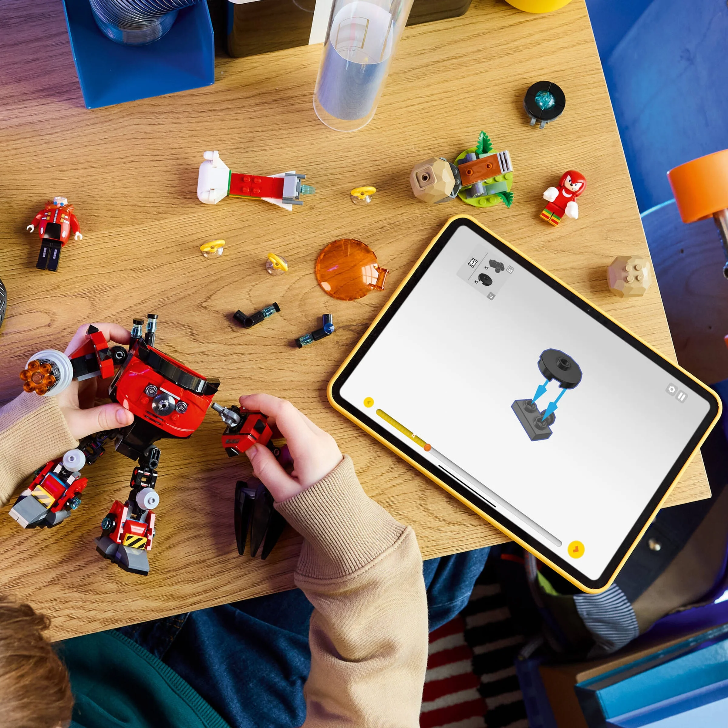 Copil asamblând setul LEGO 77005, urmând instrucțiunile digitale pe tabletă.