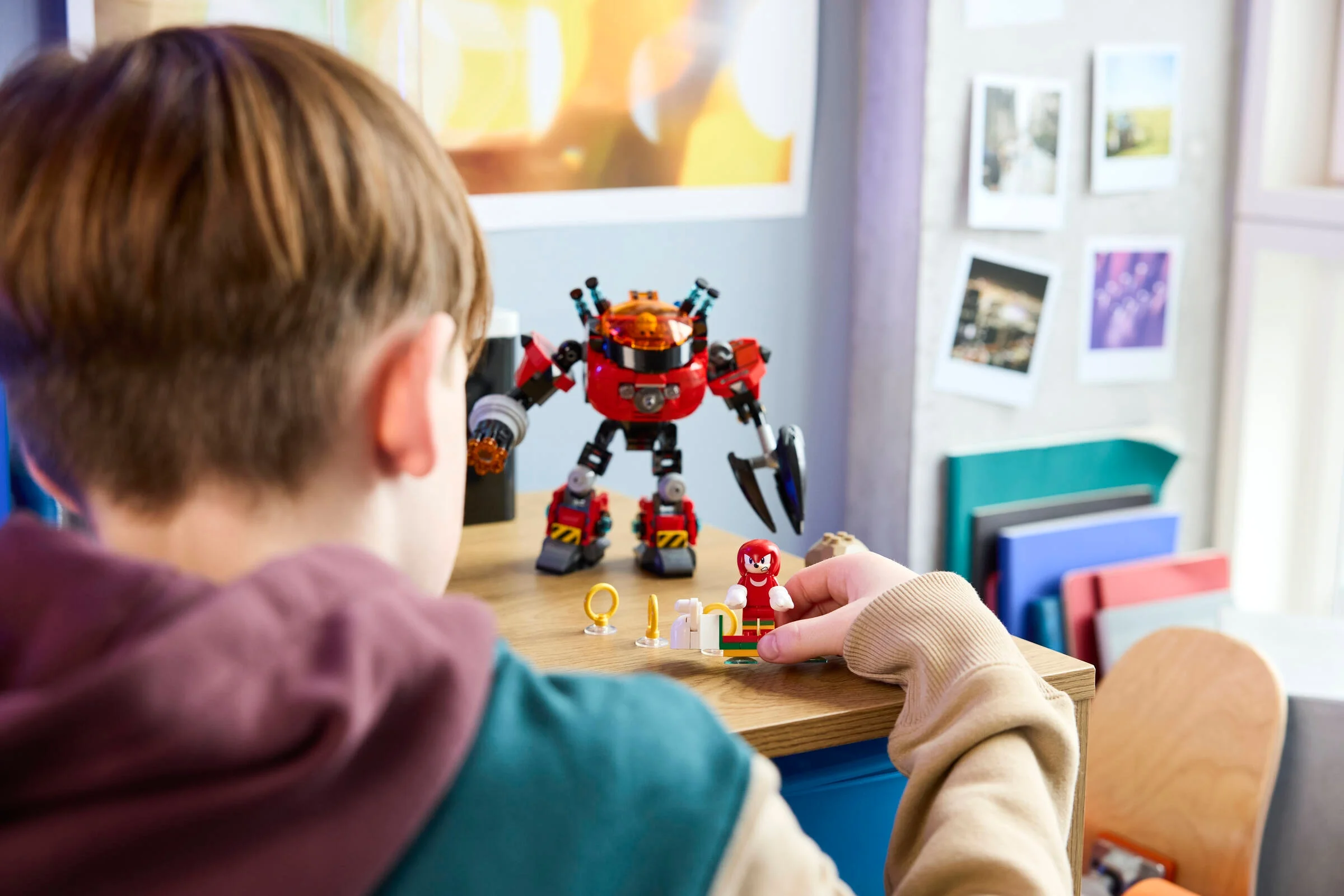 Copil se joacă cu setul LEGO Knuckles vs. Dr. Eggman. Mech-ul și minifigurinele sunt vizibile.