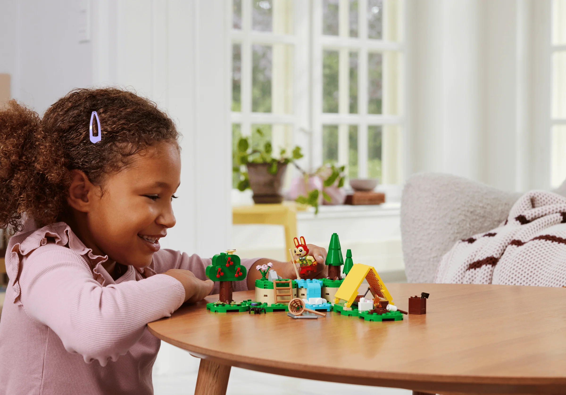 Fetiță zâmbitoare se joacă cu setul LEGO Animal Crossing în aer liber.