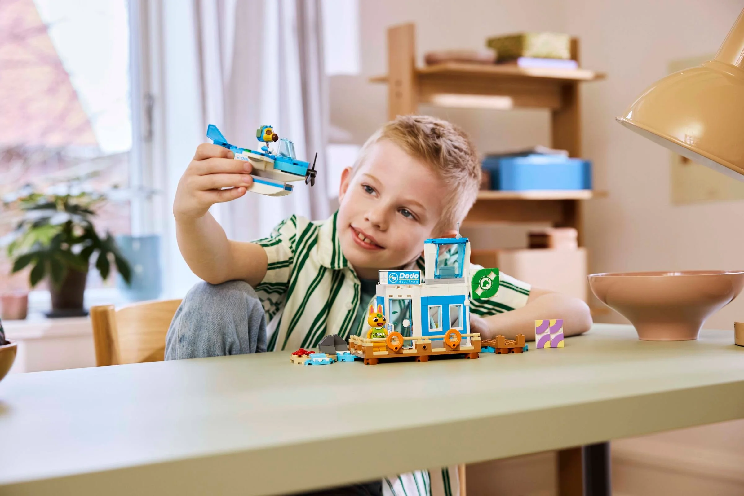 Copil se joacă cu avionul și aeroportul Dodo Airlines din setul LEGO Animal Crossing.