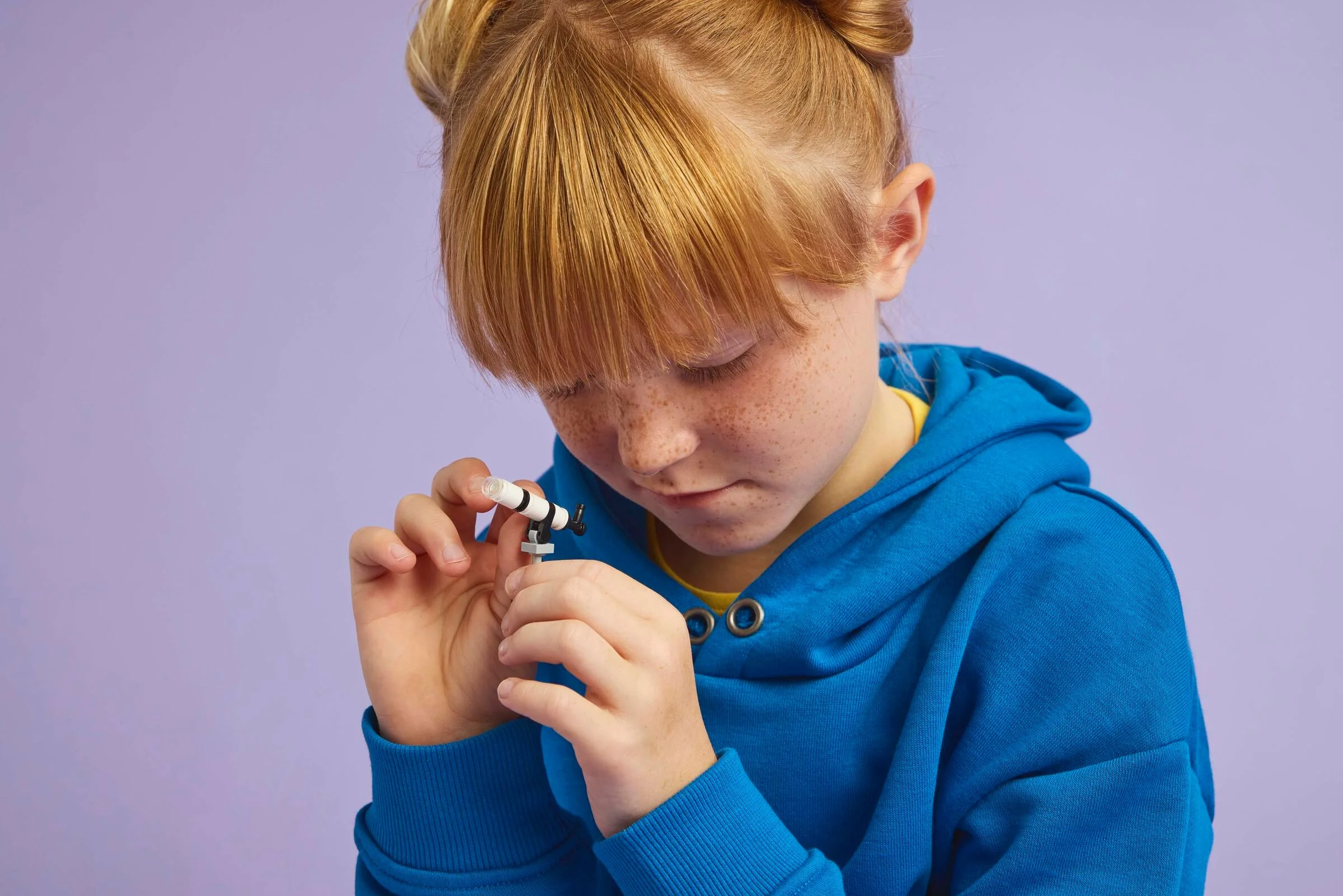 Fetiță construind telescopul LEGO din setul Animal Crossing, concentrată și zâmbitoare.
