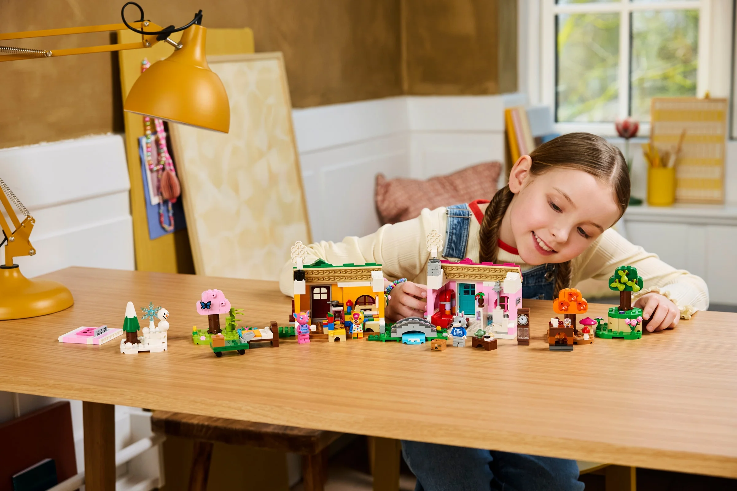 O fată zâmbind se joacă cu setul LEGO Animal Crossing, case colorate și figurine.