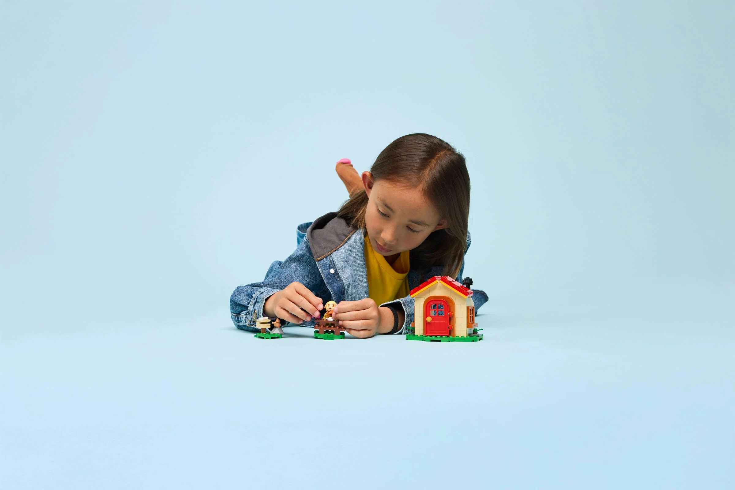 Fată jucându-se cu setul LEGO Animal Crossing Goldie's Cosy House. Casă adorabilă și minifigurine.
