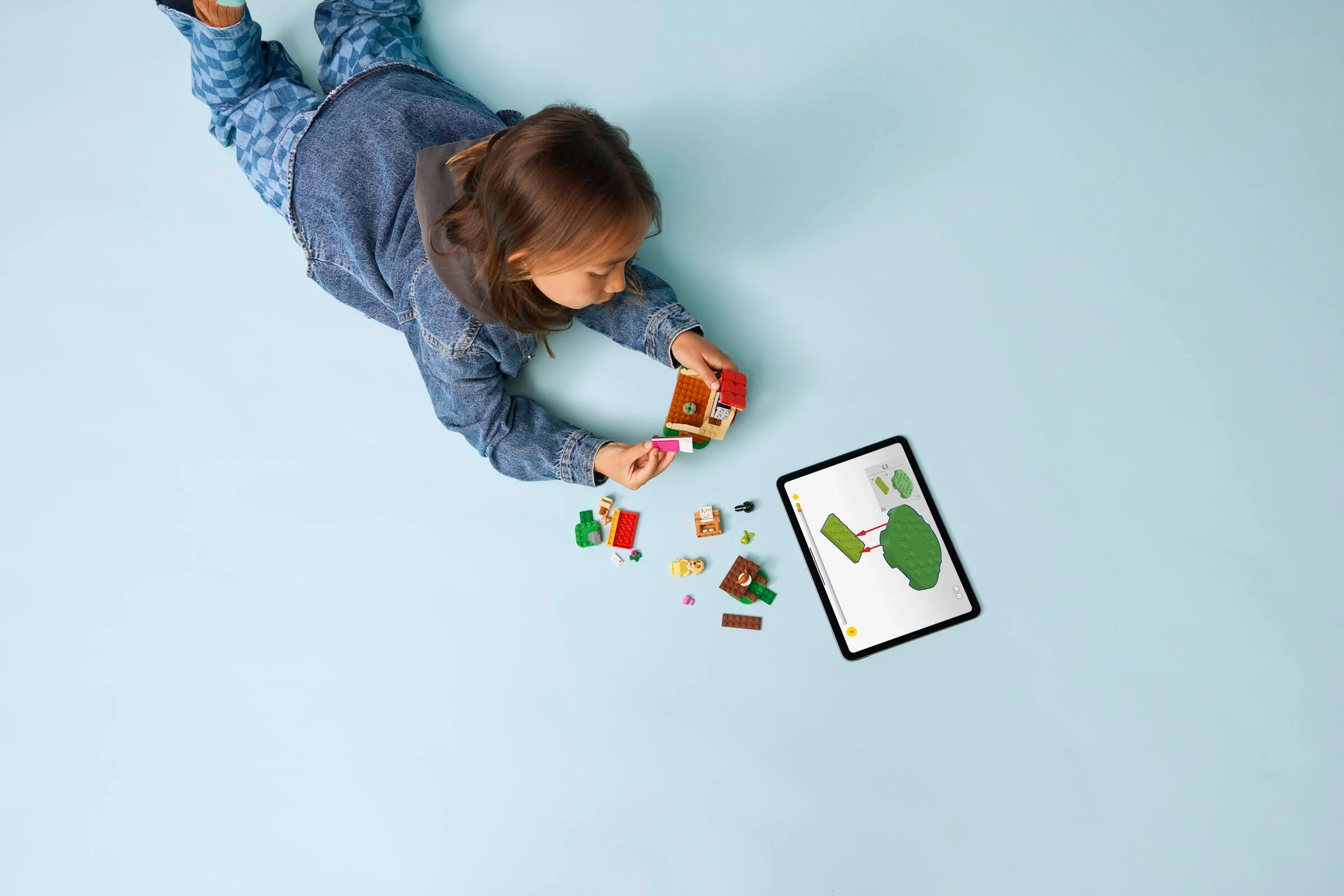 Fetiță construind căsuța LEGO Animal Crossing, urmând instrucțiuni pe tabletă.