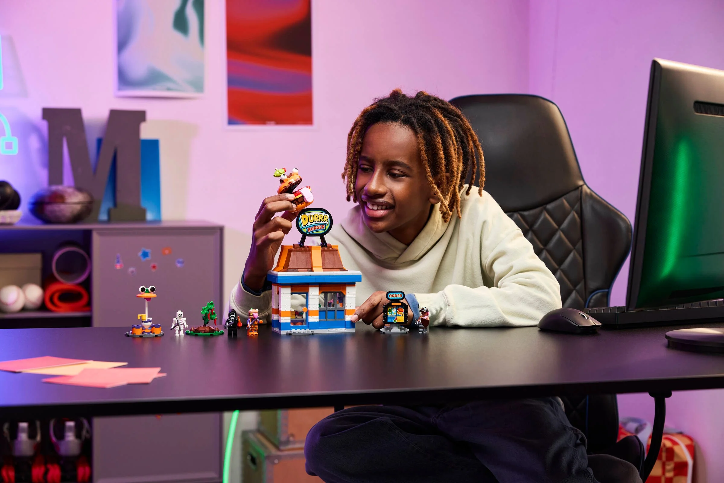 Băiat zâmbitor se joacă cu restaurantul Durrr Burger LEGO Fortnite.