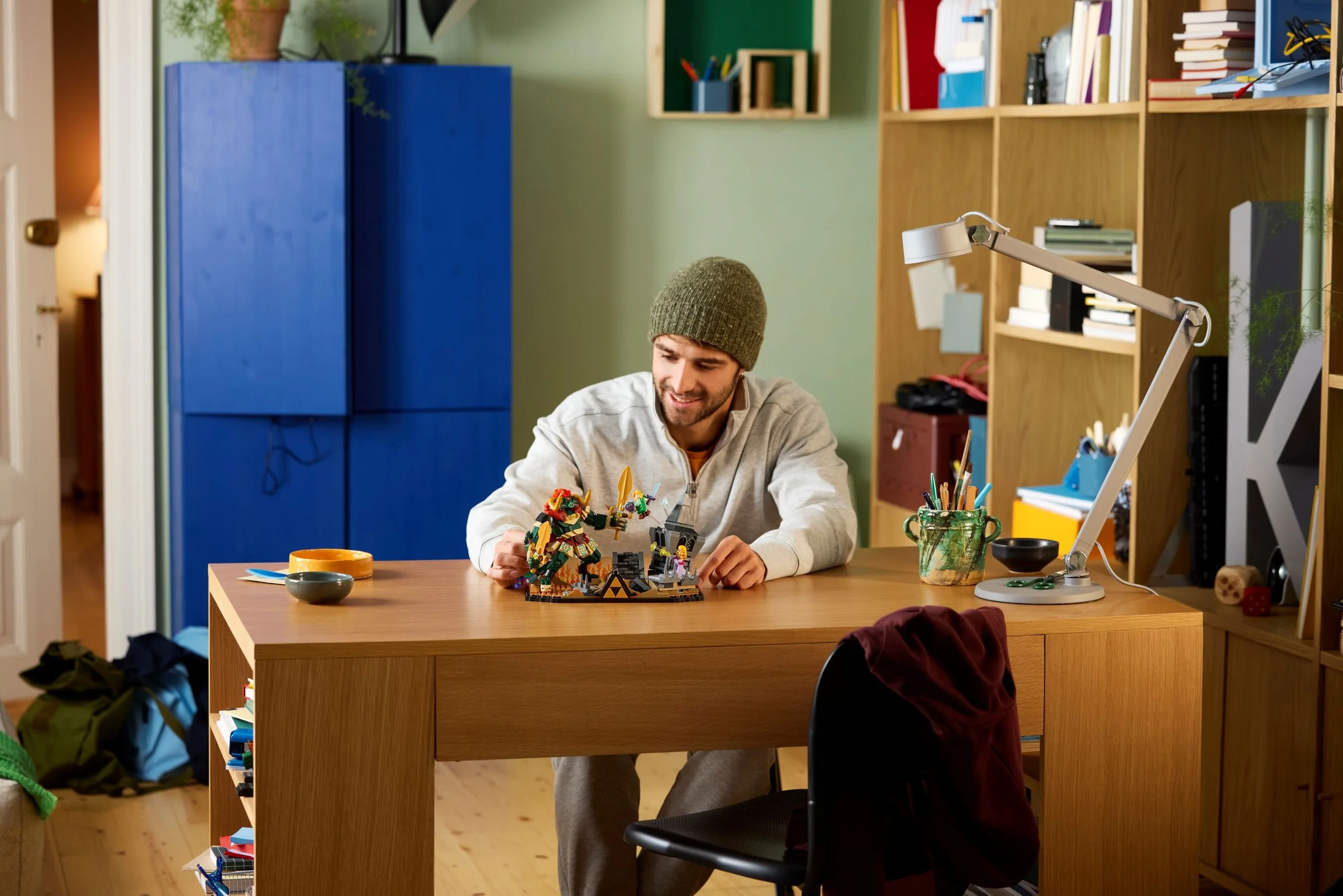 Bărbat construind setul LEGO Zelda, scena bătăliei finale, pe biroul său.