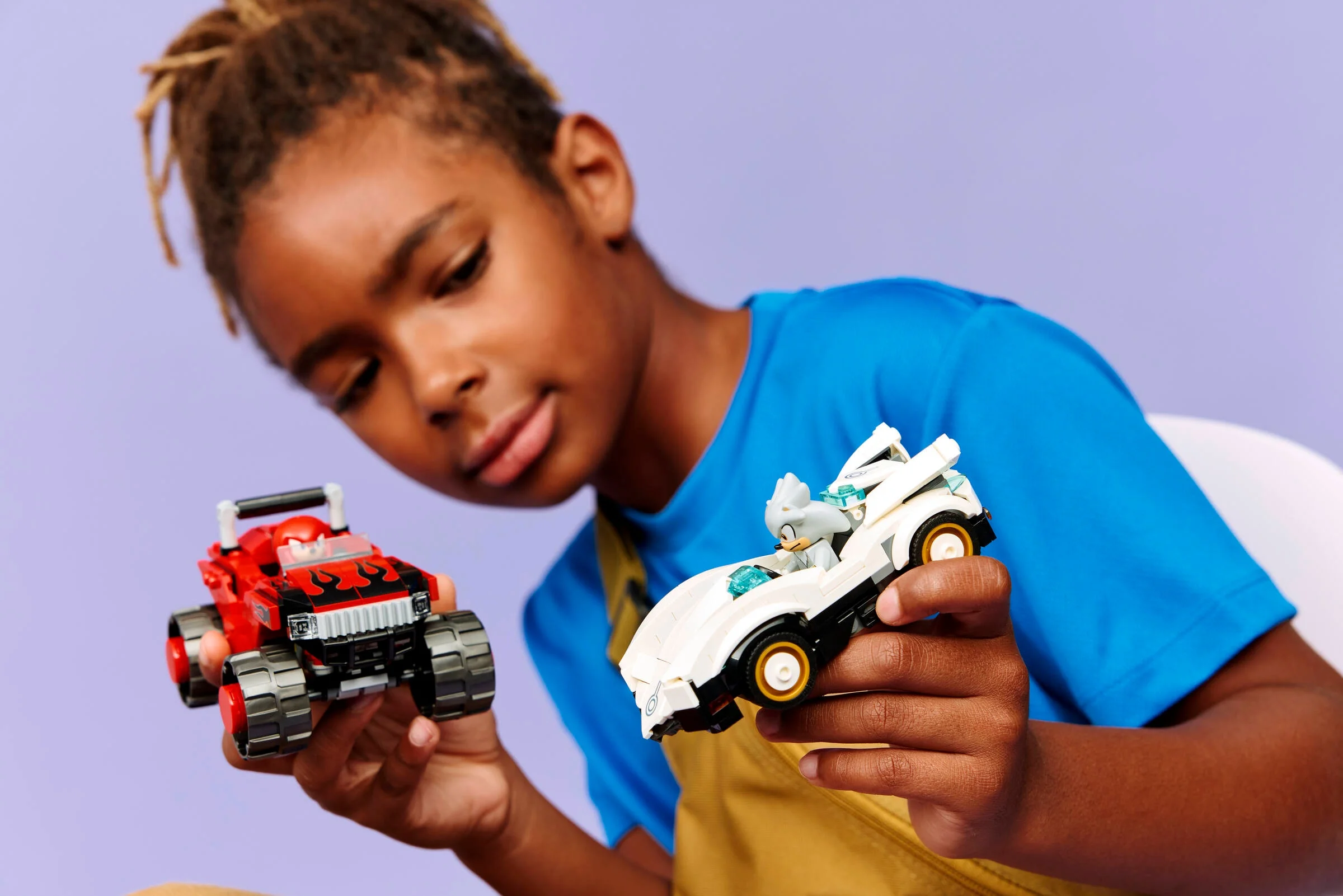 Copil se joacă cu mașina lui Silver și monster truck-ul lui Knuckles din setul LEGO Sonic.