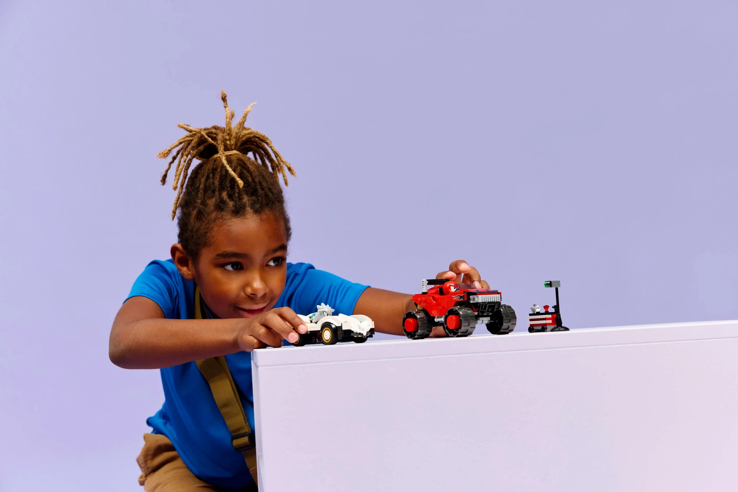 Copil se joacă cu setul LEGO „Mașina lui Silver vs. Monster Truck-ul lui Knuckles”.