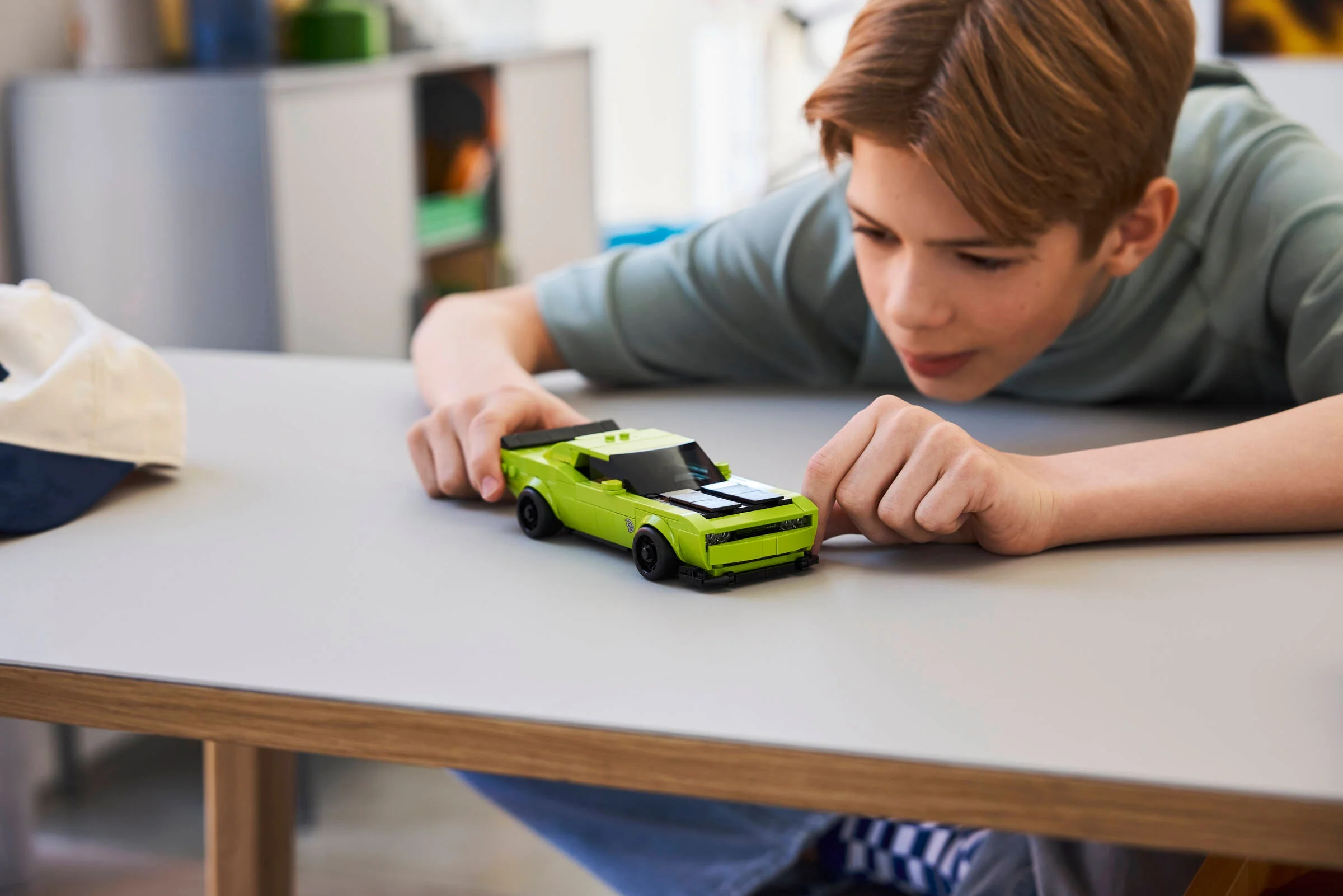 Un băiat se joacă cu mașina Dodge Challenger SRT Hellcat LEGO, concentrat și entuziasmat.