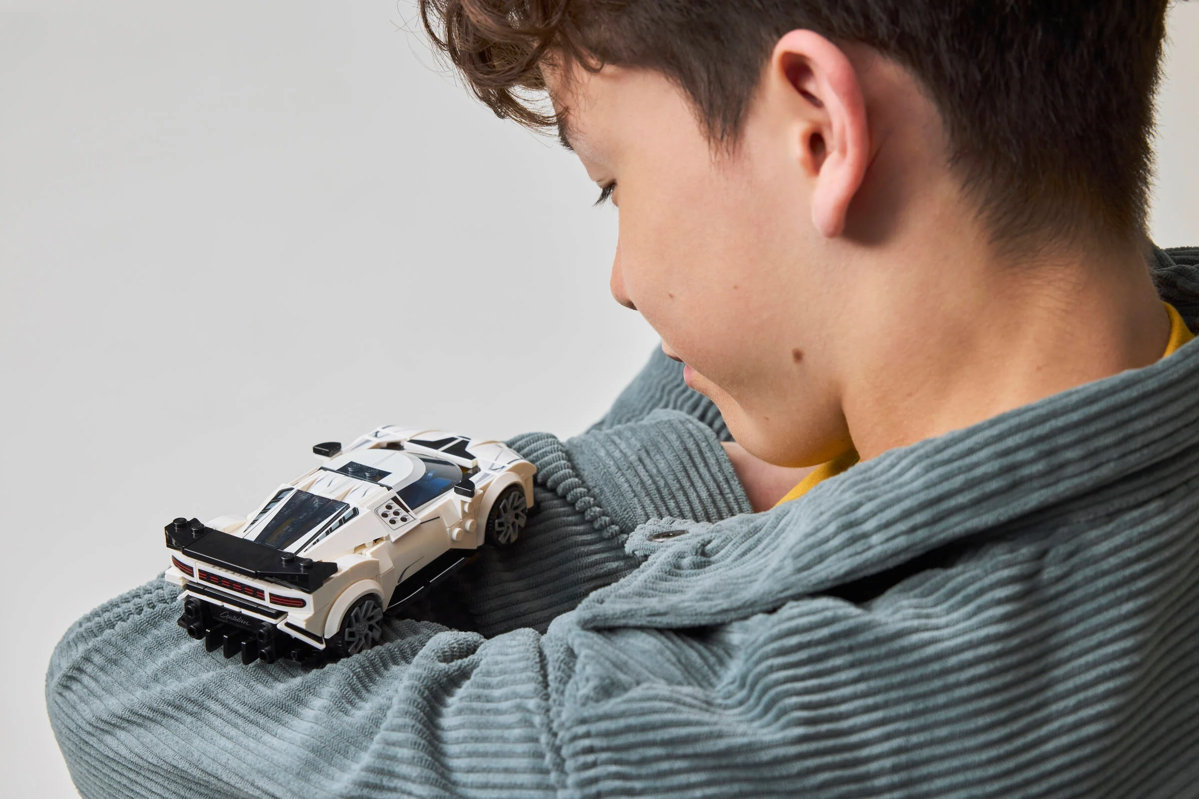 Copil admirând mașina Bugatti Centodieci LEGO. Atenție la detalii și bucuria jocului.