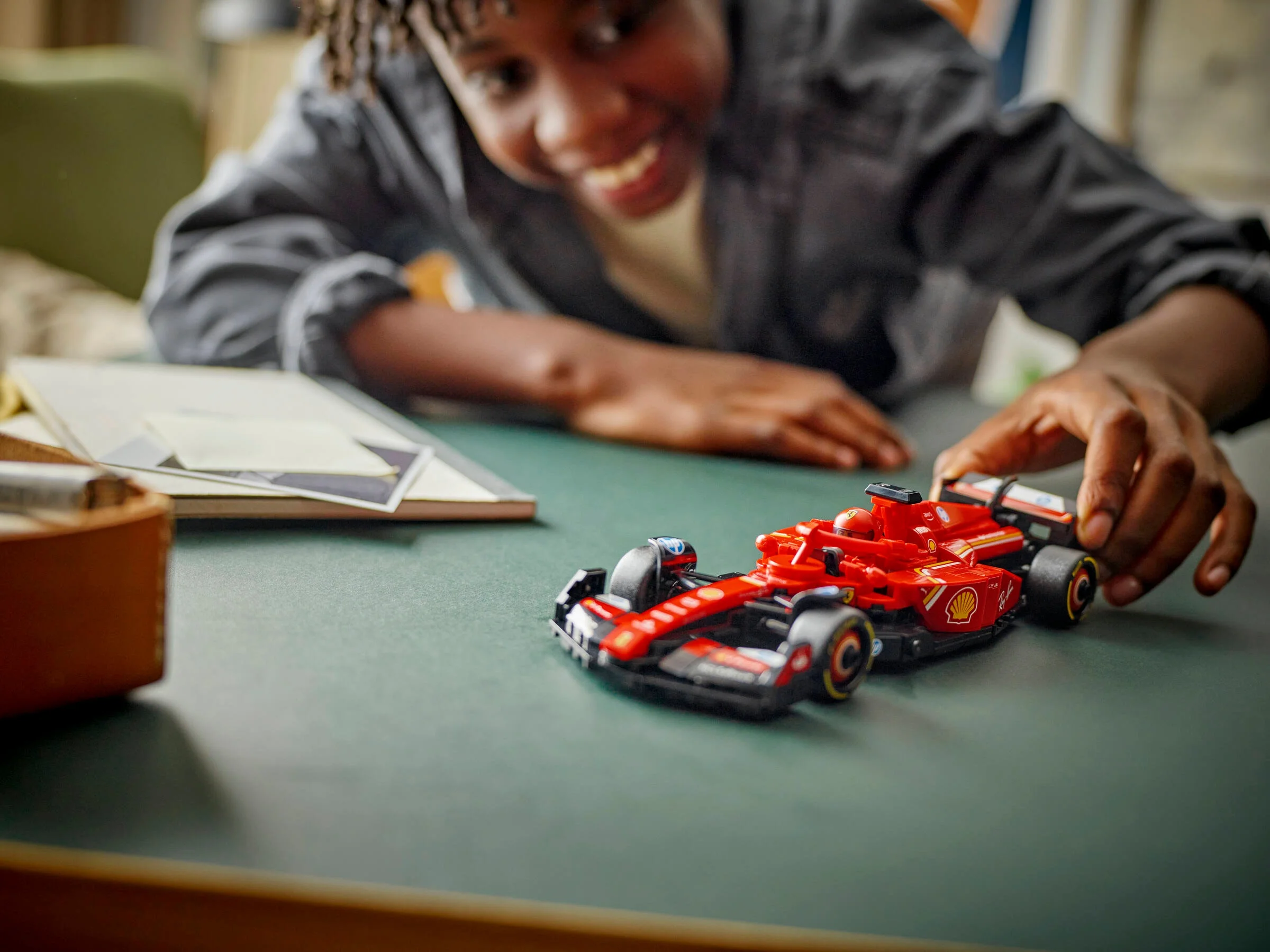 Băiat zâmbitor se joacă cu modelul LEGO Ferrari SF-24, bucurându-se de creație.