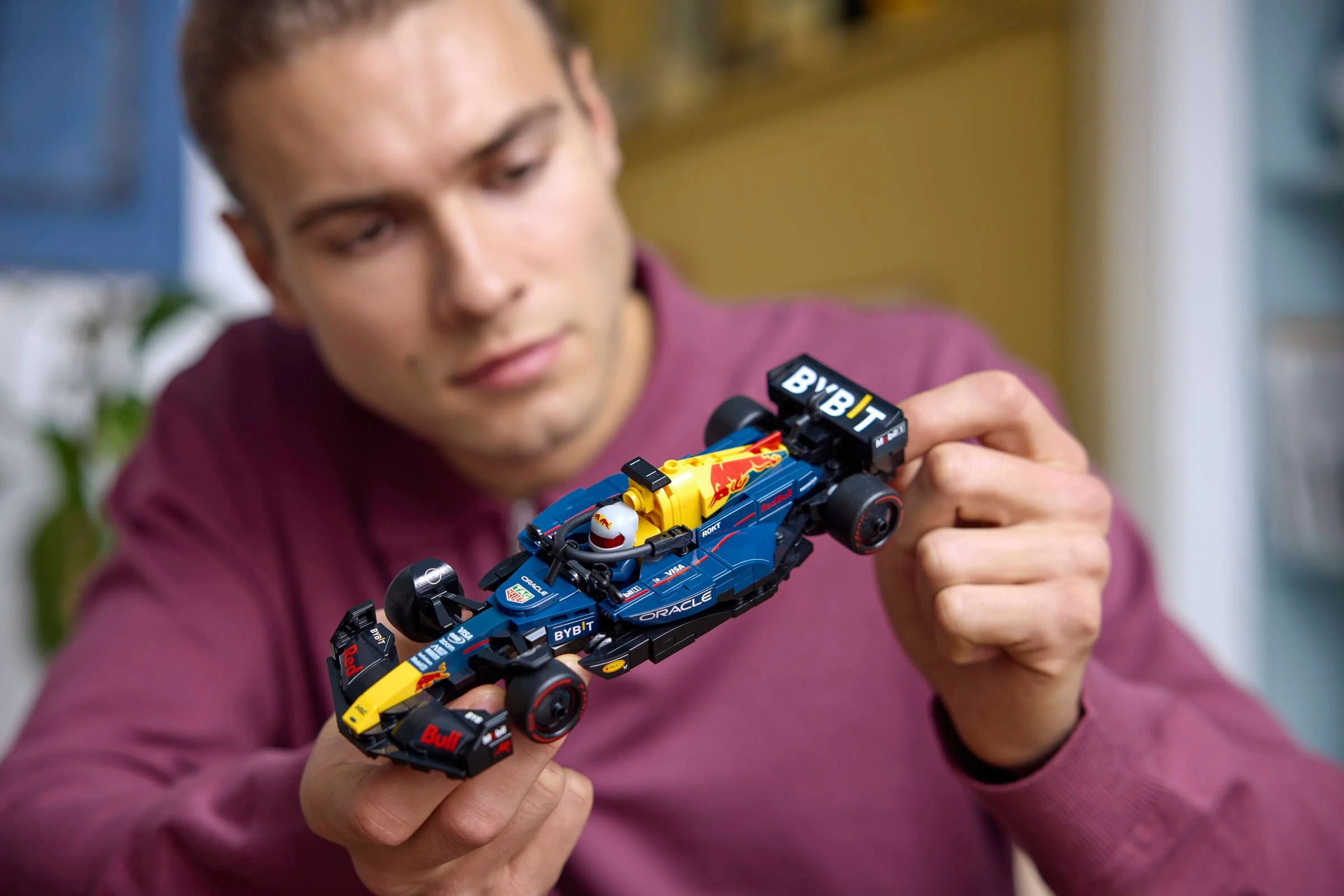 Un adult ține modelul LEGO al mașinii Oracle Red Bull Racing RB20.