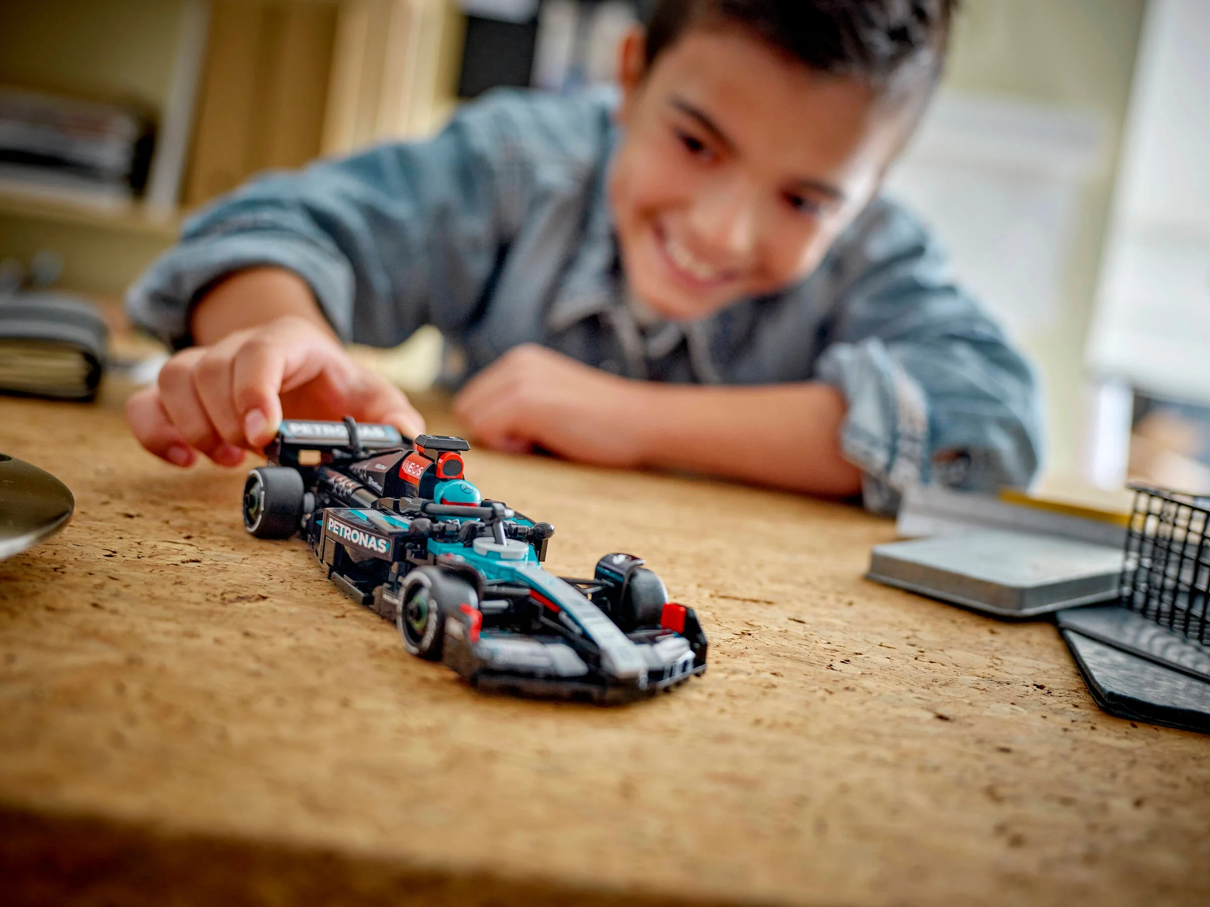 Băiat zâmbitor se joacă cu mașina LEGO Mercedes F1. Model detaliat, atrăgător.