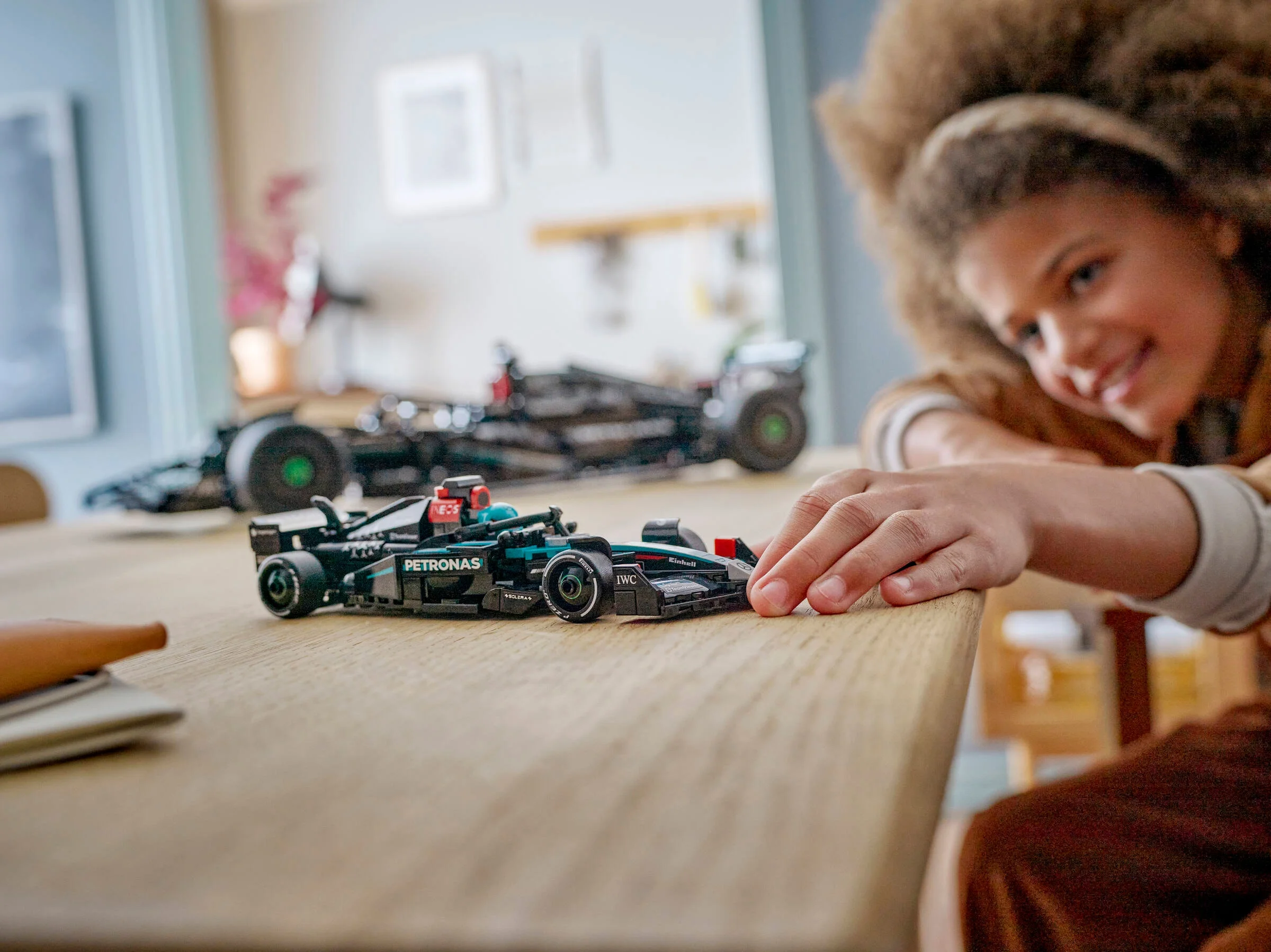O fetiță se joacă cu mașina de curse Mercedes-AMG PETRONAS F1 W15.