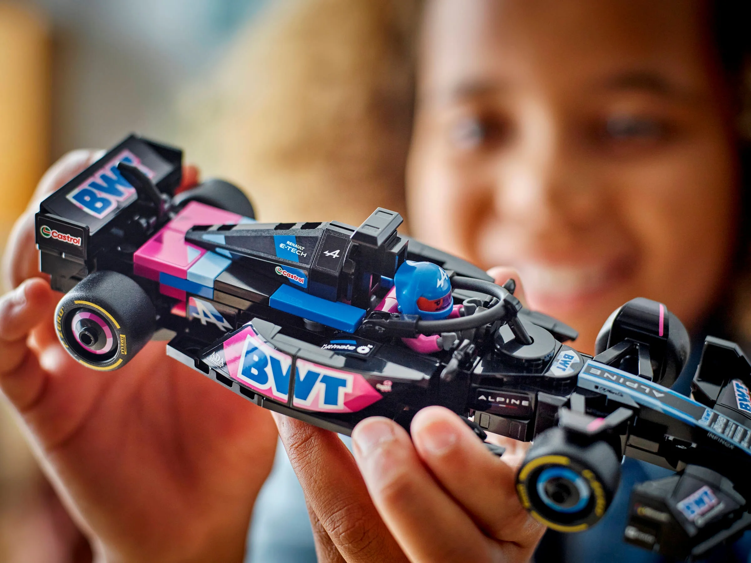 O fată ține în mână modelul LEGO BWT Alpine F1 Team A524, arătând detaliile mașinii.