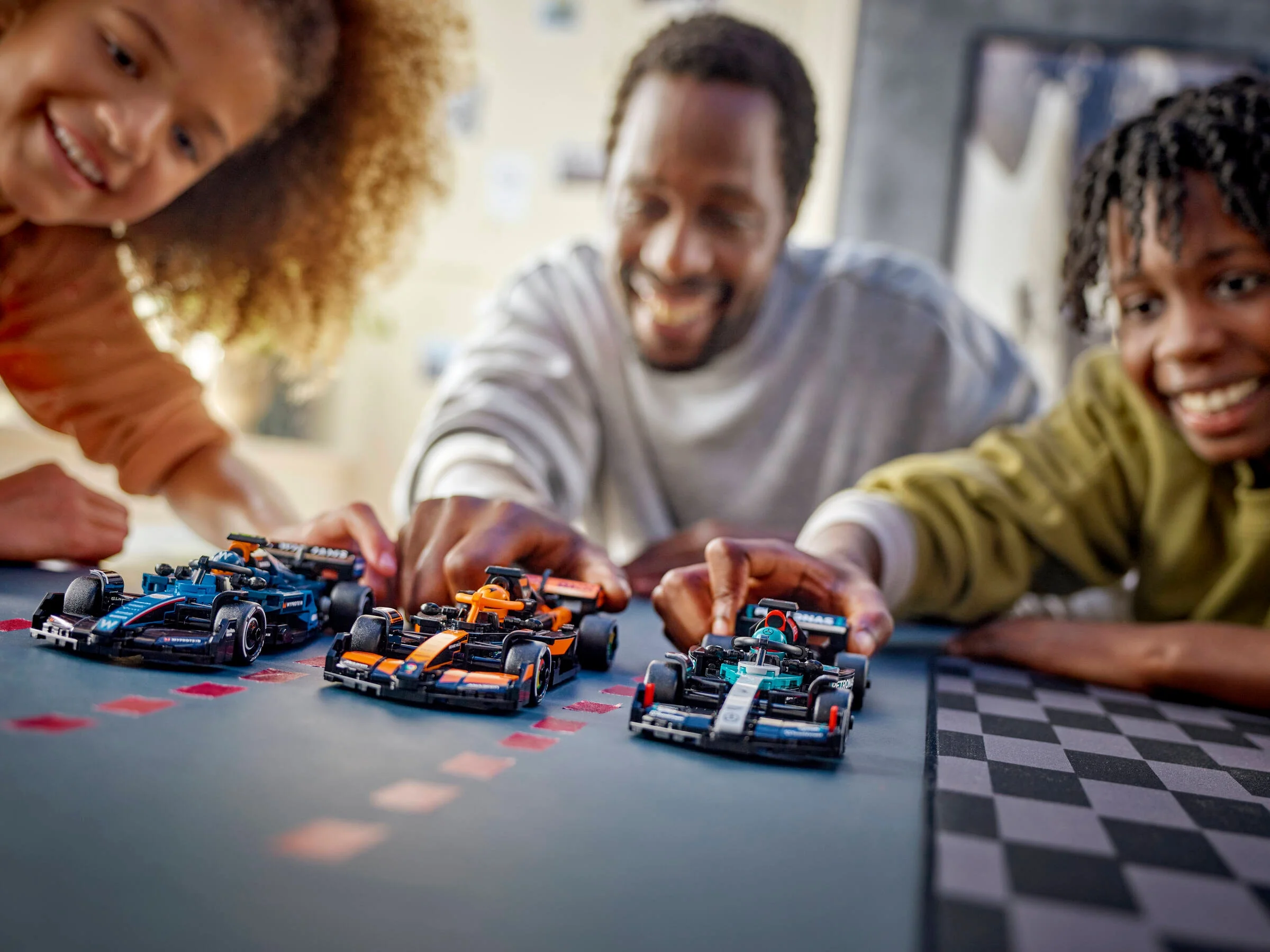 Imagine cu setul LEGO McLaren F1 Team MCL38 și o familie care se joacă cu modelele.