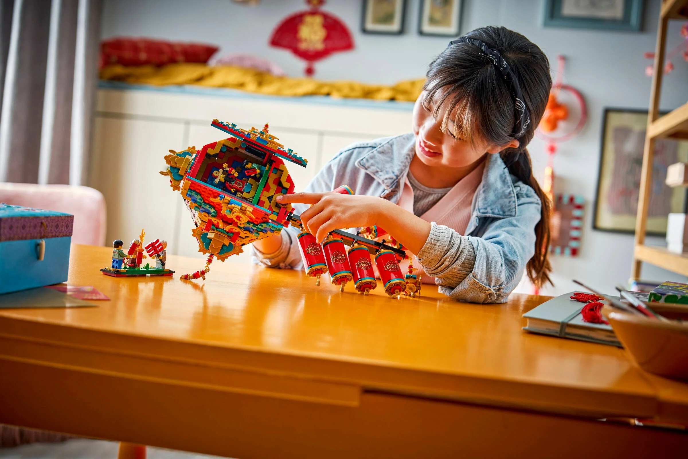 O fată interacționează cu setul LEGO Fortune Firecracker, pe o masă luminoasă.