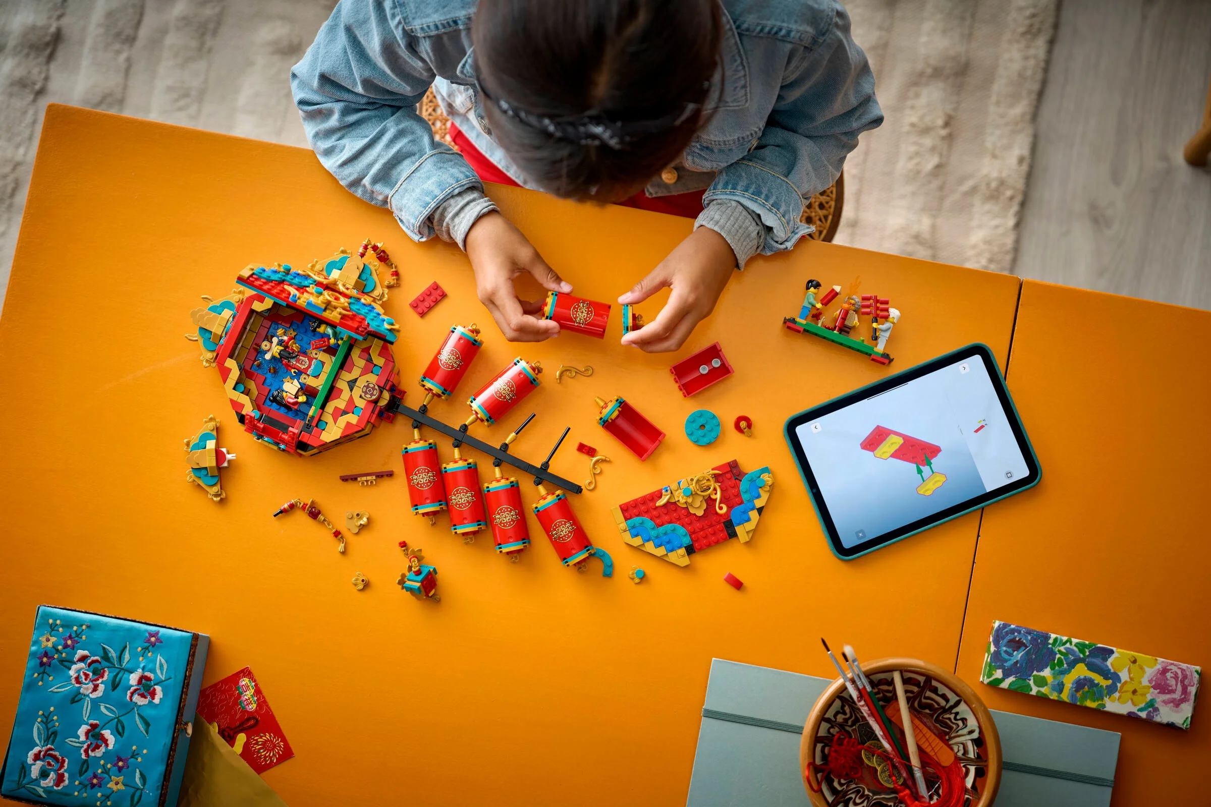 O fetiță construiește setul LEGO 80118 „Petarde Norocoase” folosind instrucțiuni digitale pe tabletă.