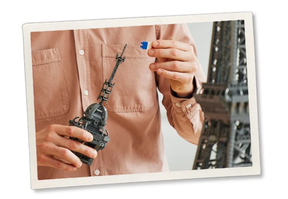 Construind detaliile turnului Eiffel LEGO. O piesă albastră este adăugată structurii gri.