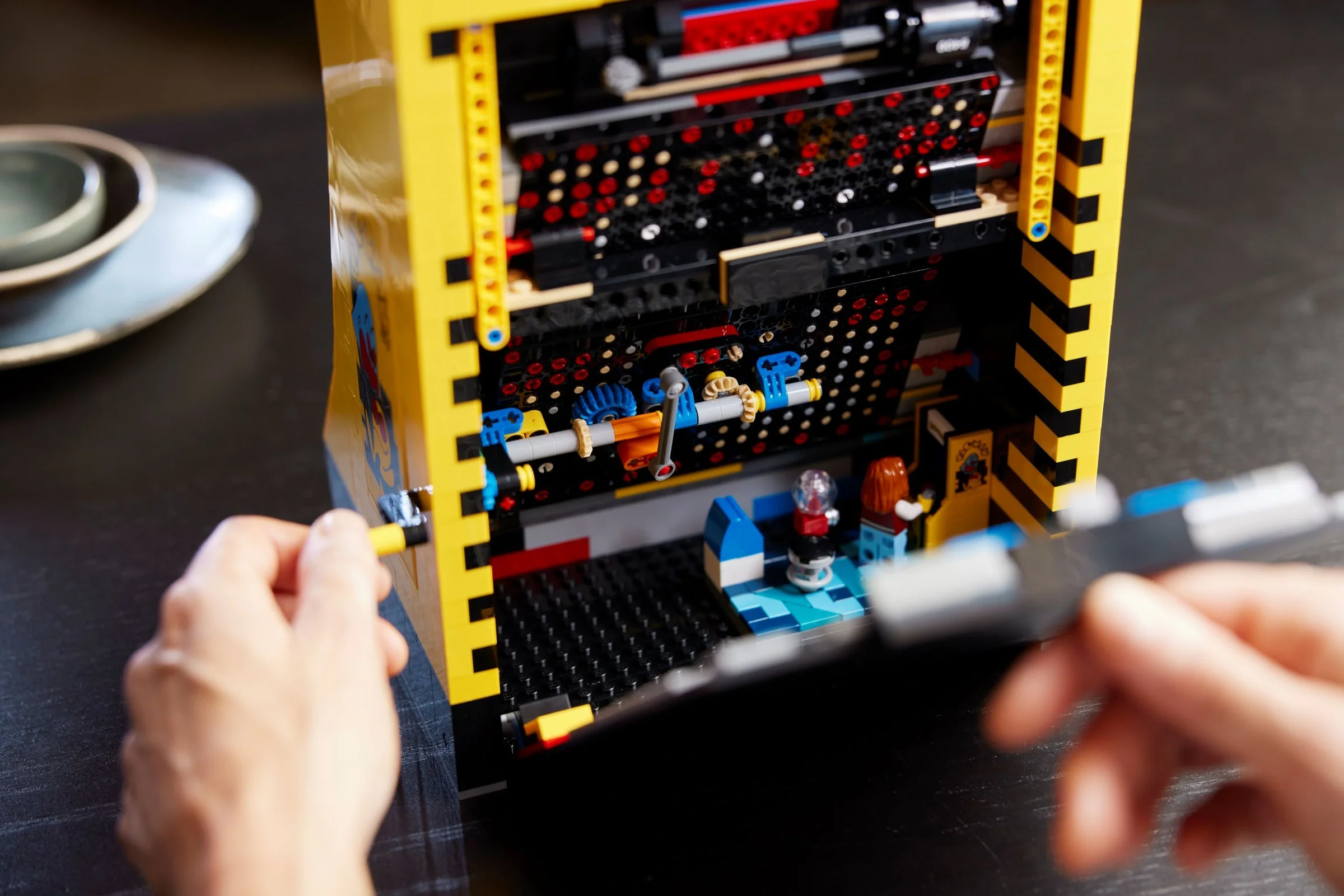 Vedem interiorul detaliat al arcadei Pac-Man, cu minifigurine și mecanisme interne.