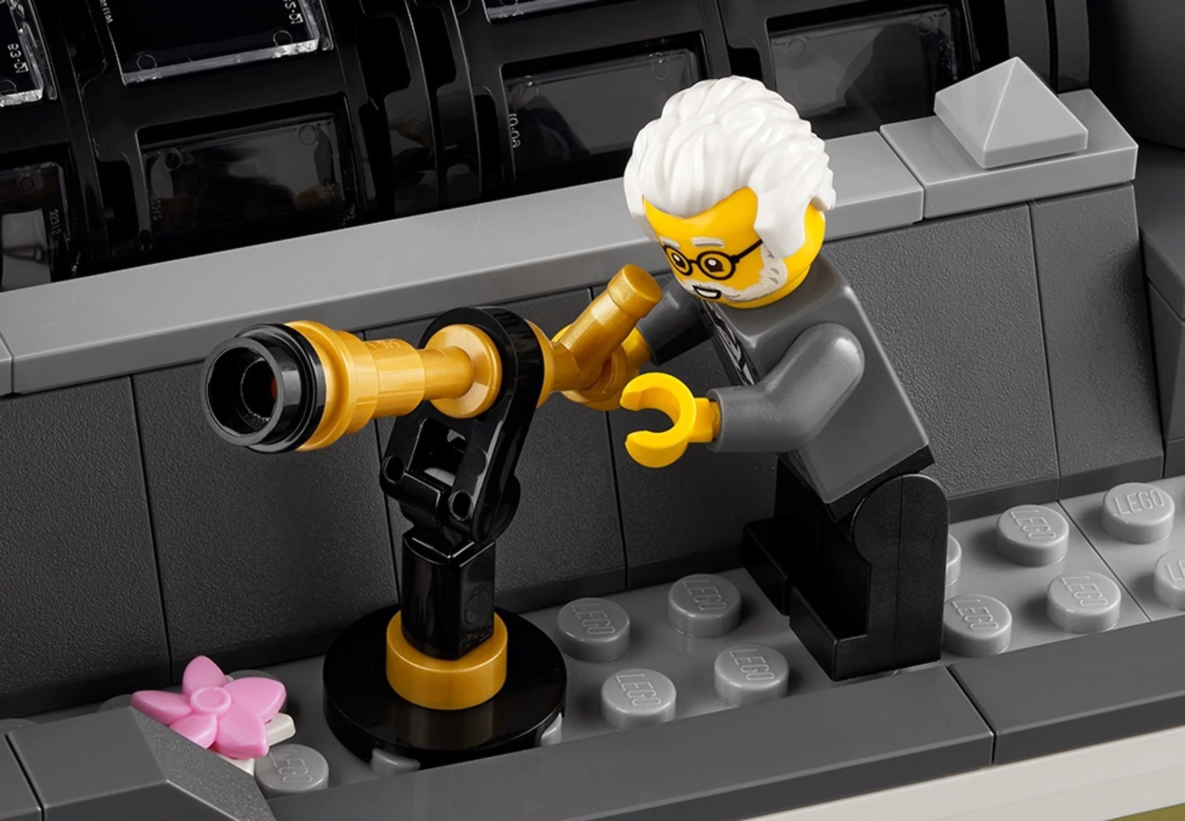 Prim-plan cu o minifigurină LEGO examinând un telescop aurit în muzeu.