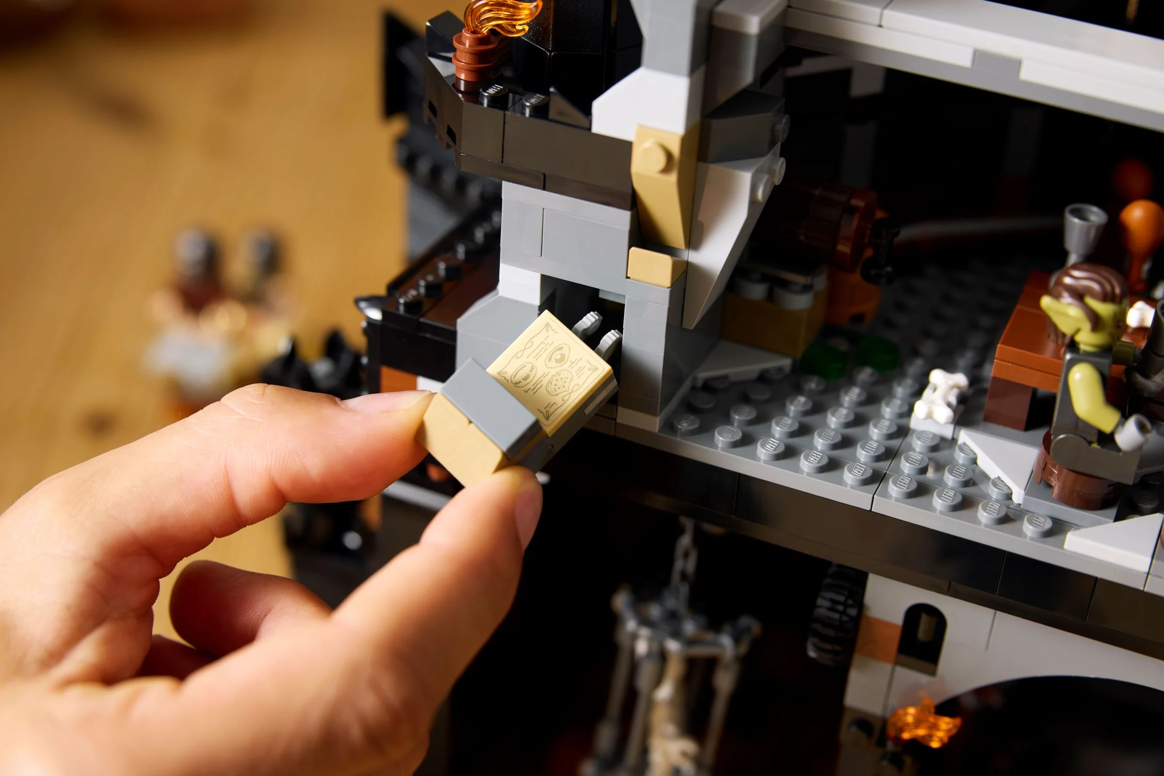 Imagine detaliată cu o mână introducând un pergament LEGO într-un compartiment al Barad-dûr.