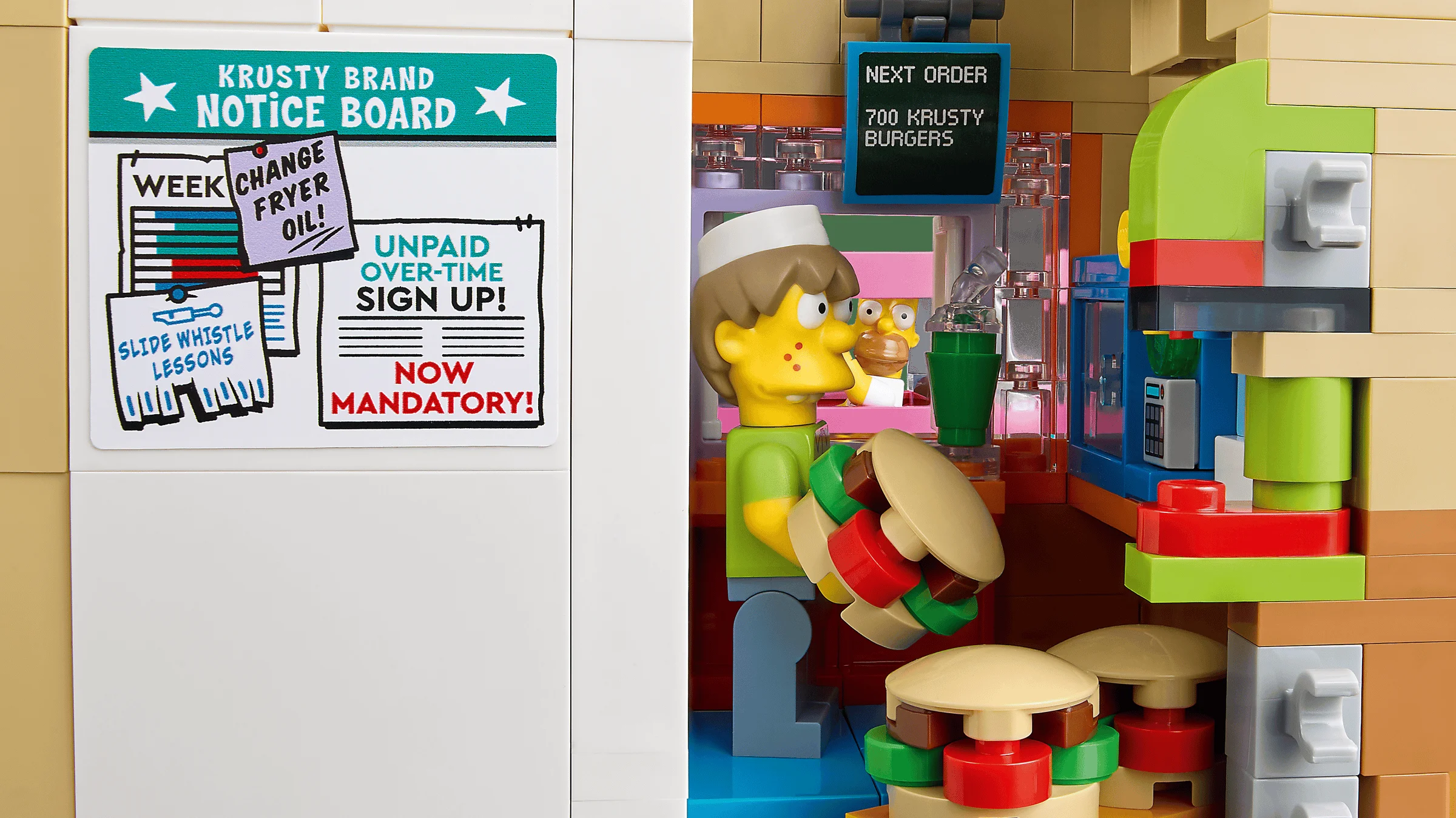 Prim-plan cu detalii din Krusty Burger LEGO: avizier, minifigurina angajat și zona de preparare.