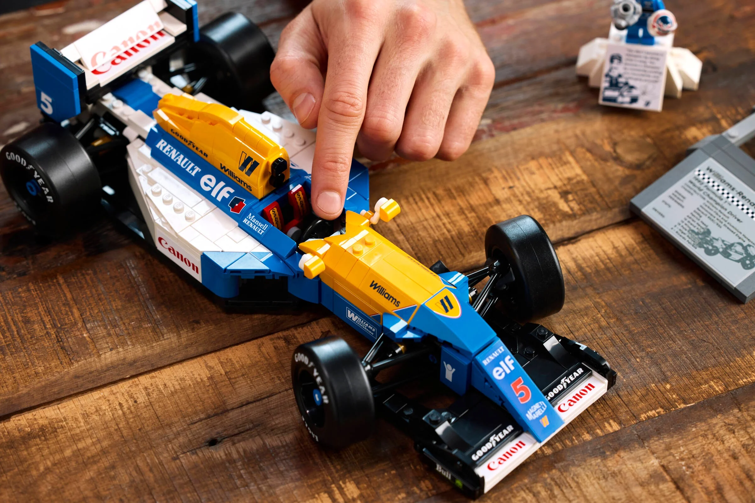 Mână interacționând cu Williams FW14B LEGO. Vedere detaliată a mașinii și a componentelor.