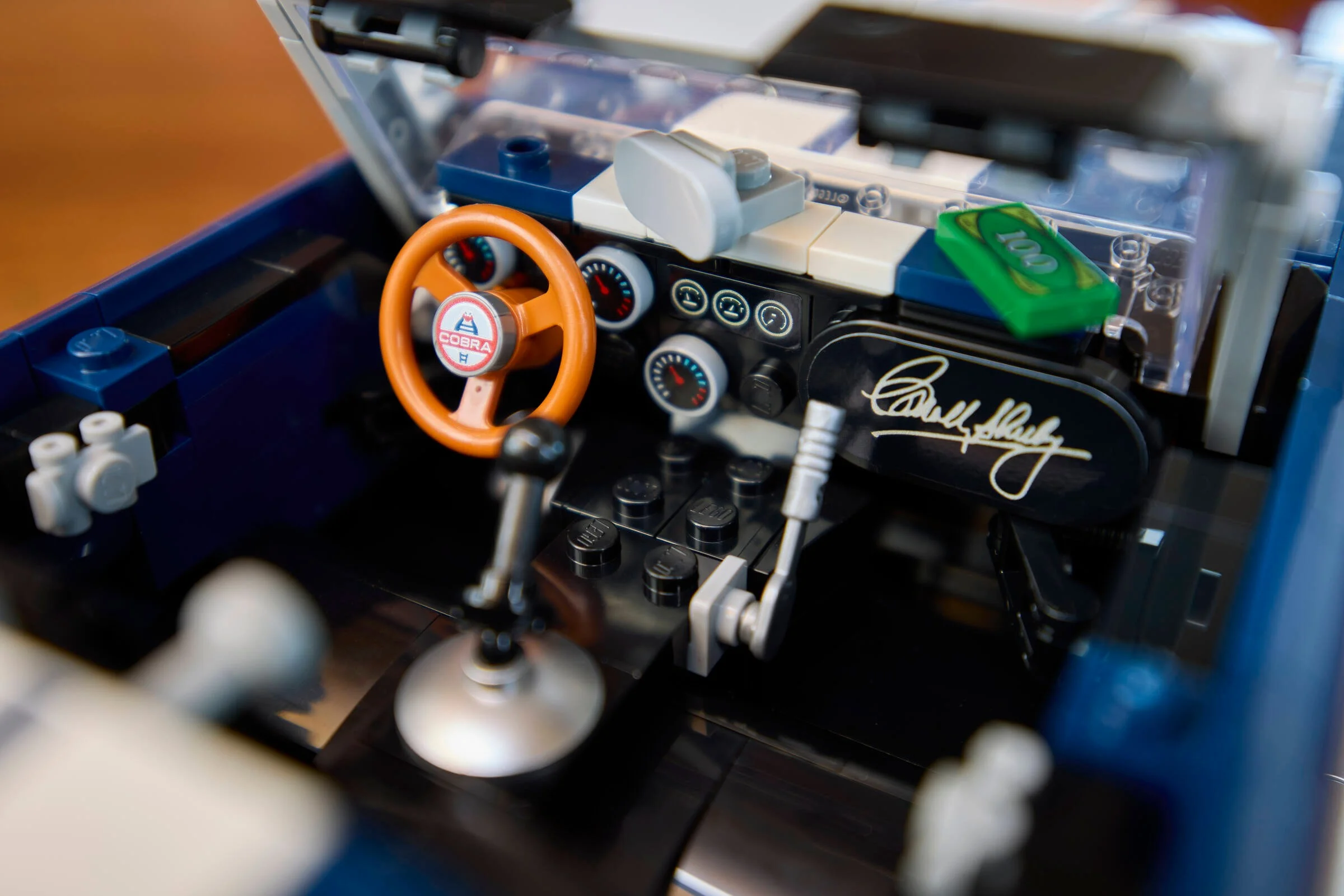 Interiorul detaliat al mașinii Shelby Cobra, cu volan, schimbător și alte detalii autentice.