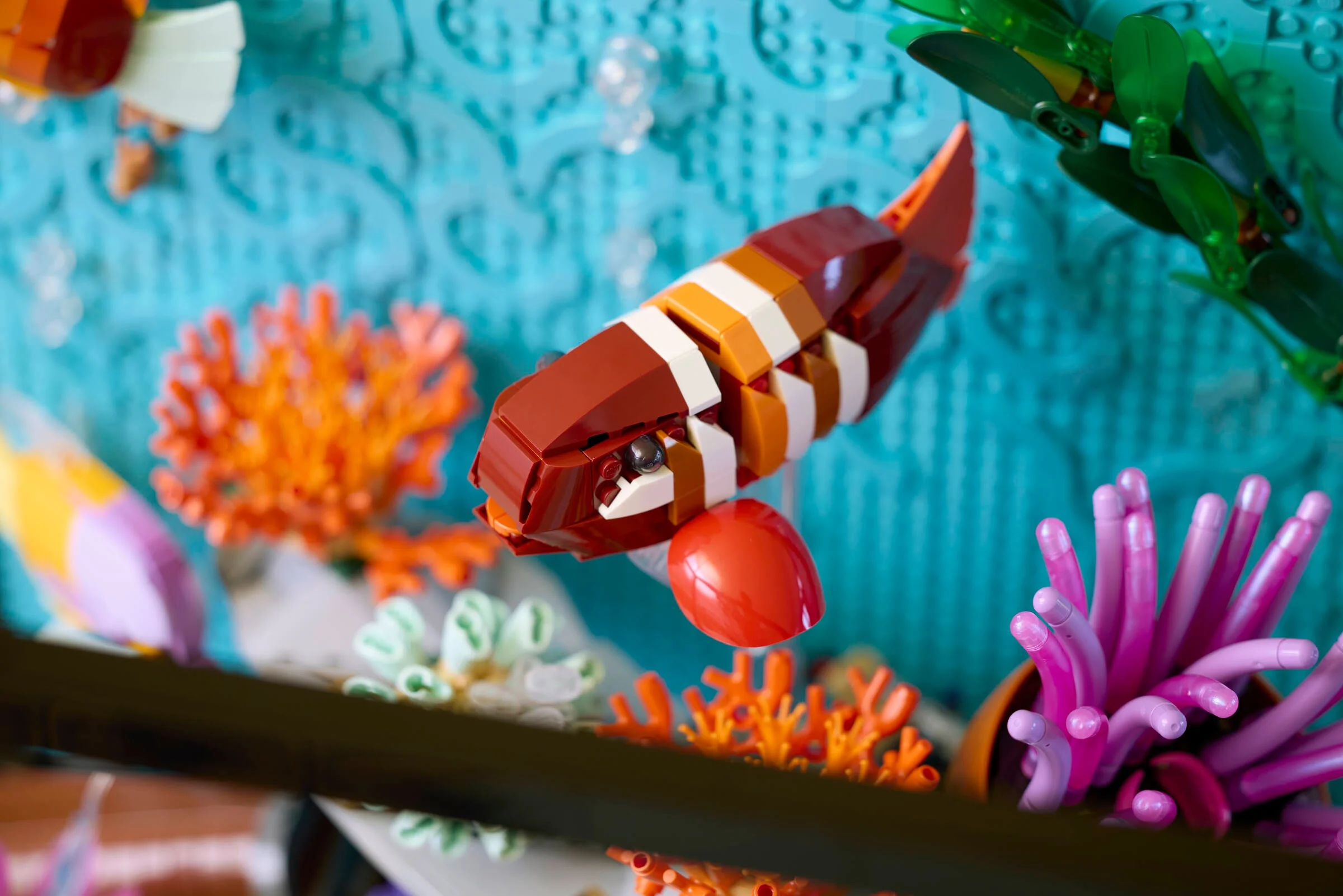 Prim plan cu un pește clovn construit din LEGO, într-un acvariu tropical LEGO detaliat.