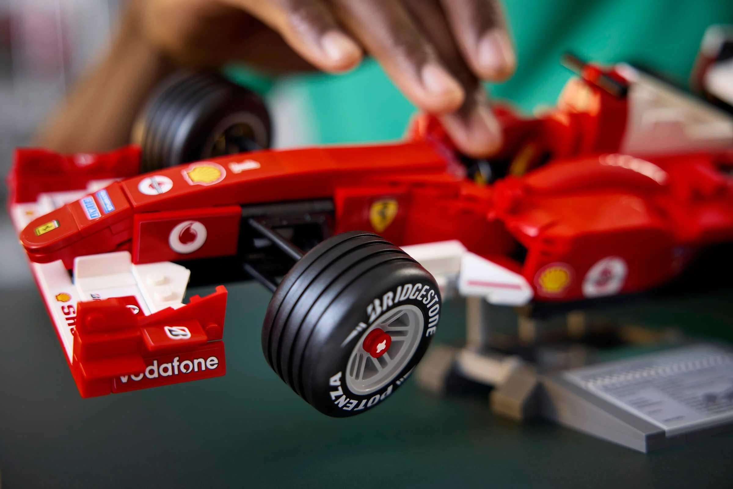 Prim-plan cu Ferrari F2004 din LEGO, cu detalii ale roții și ale sponsorilor, în construcție. 