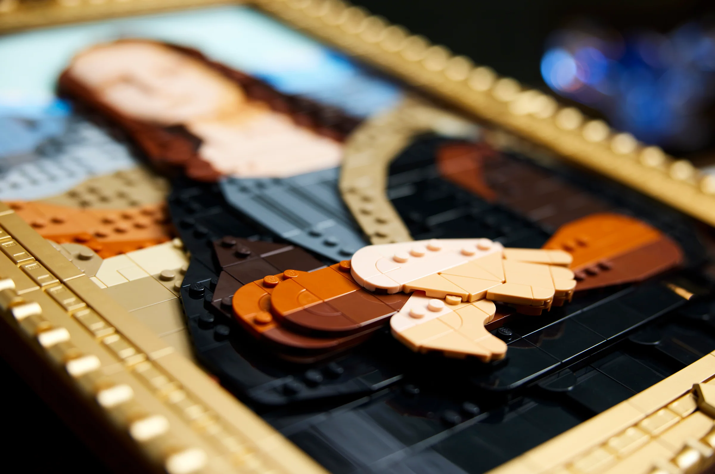 Prim plan al detaliilor fine ale modelului LEGO Mona Lisa, cu rame aurii.