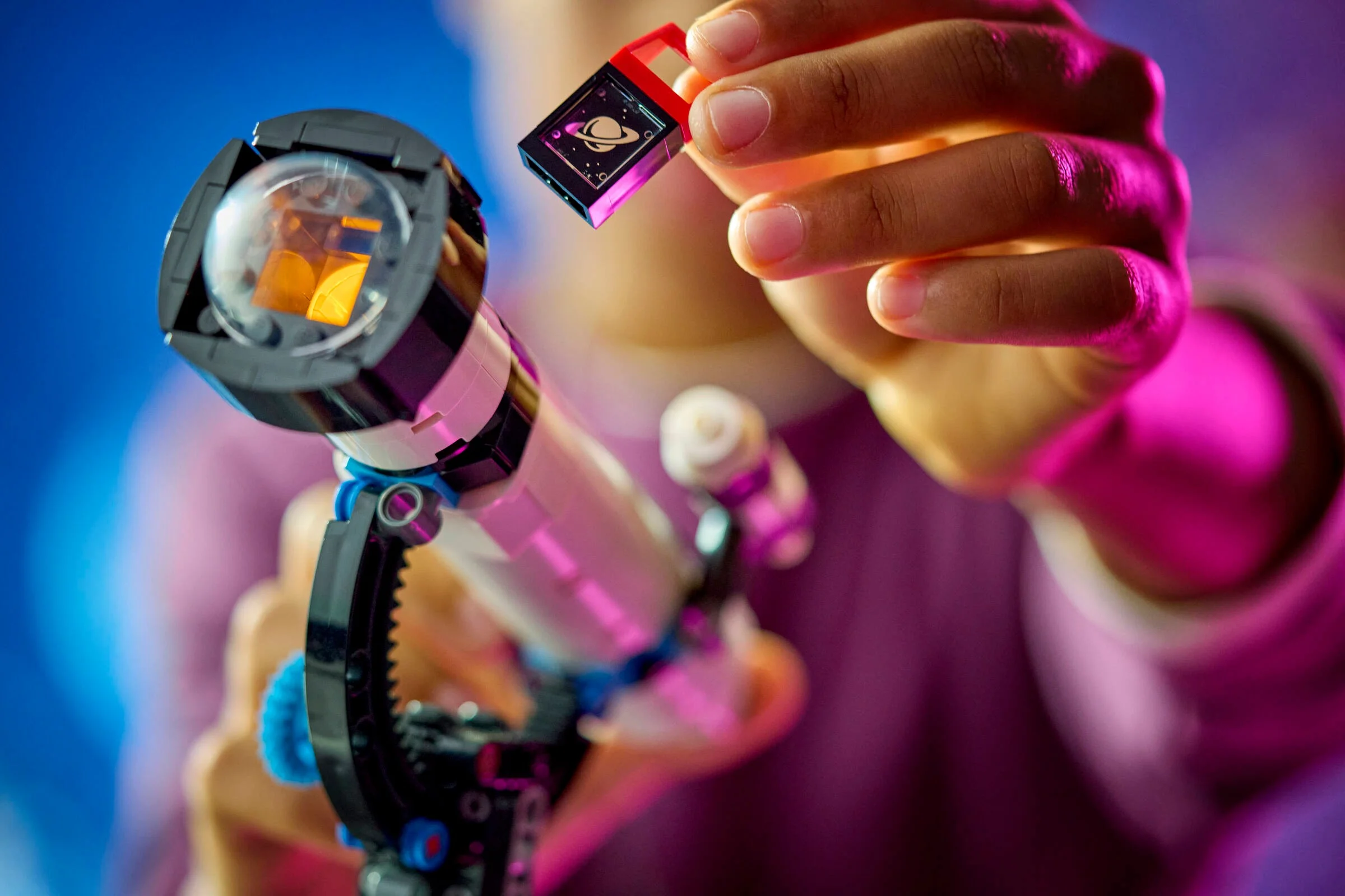 Prim-plan cu telescopul spațial LEGO și o lentilă cu imaginea lui Saturn, explorare astronomică.