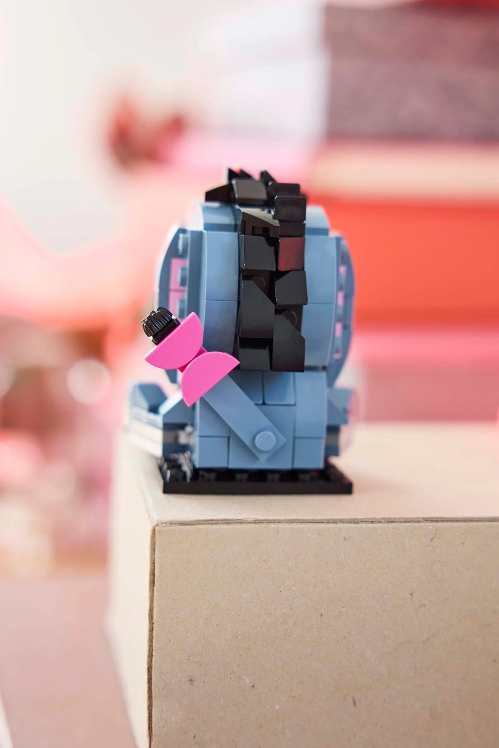 Prim-plan cu Eeyore BrickHeadz văzut din spate, cu fundița roz și coama neagră vizibile.