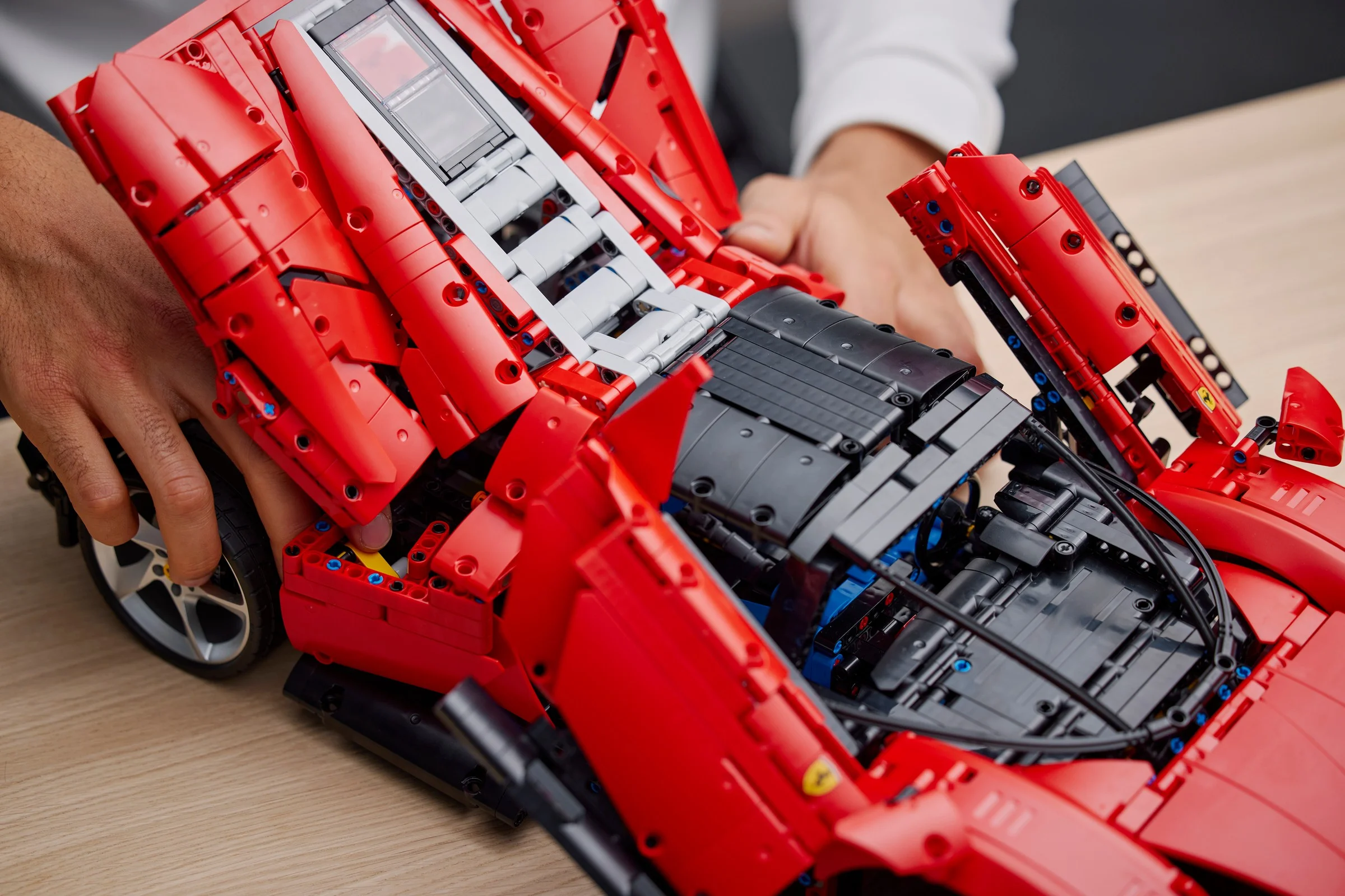 Detalii ale motorului Ferrari Daytona SP3, cu capota și ușile deschise, prezentând complexitatea construcției.